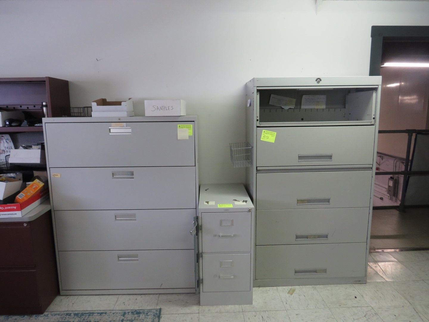 Three gray metal file cabinets of varying sizes against a white wall.