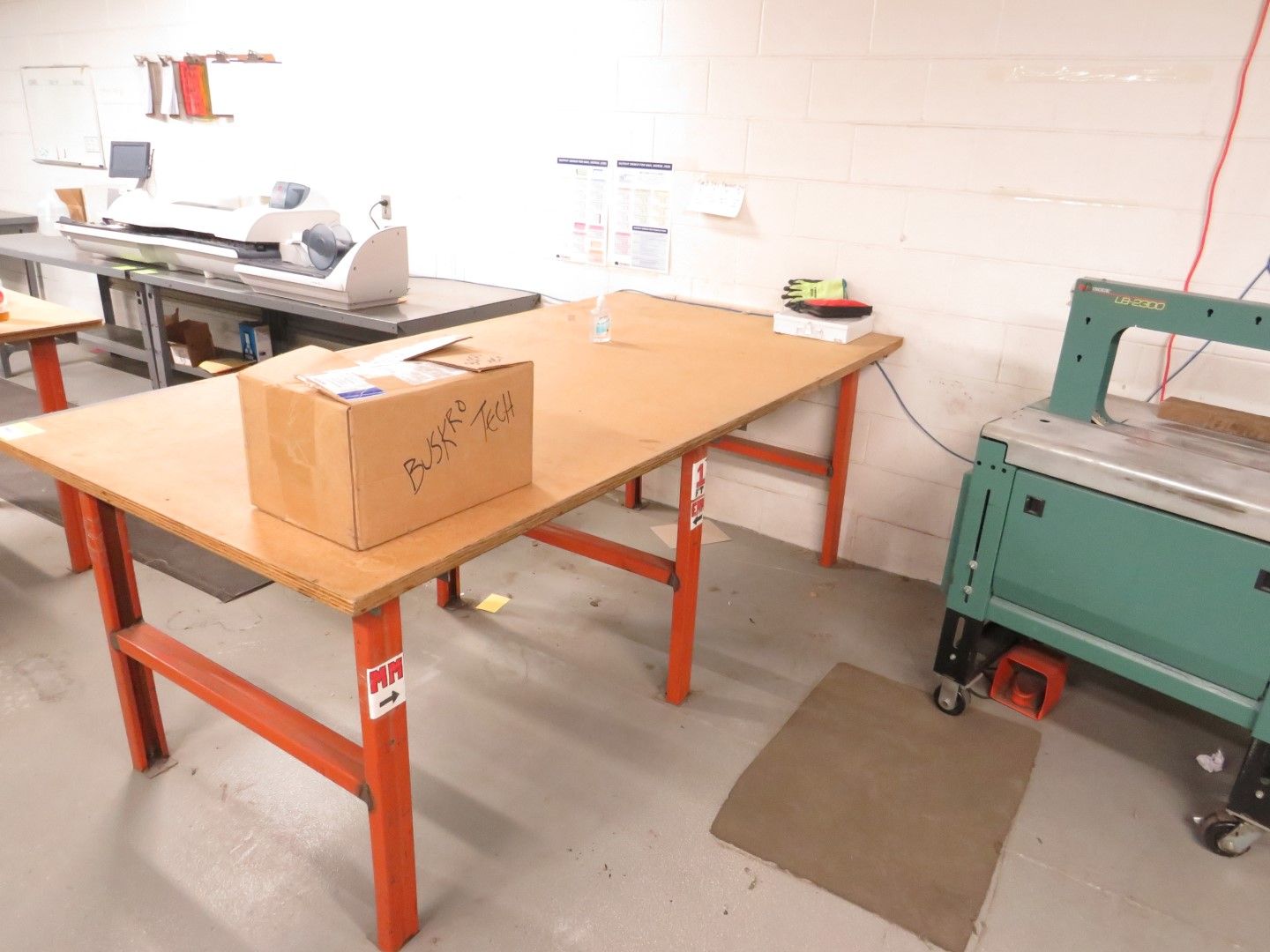 A work area with a long table, a box, and a cutting machine.