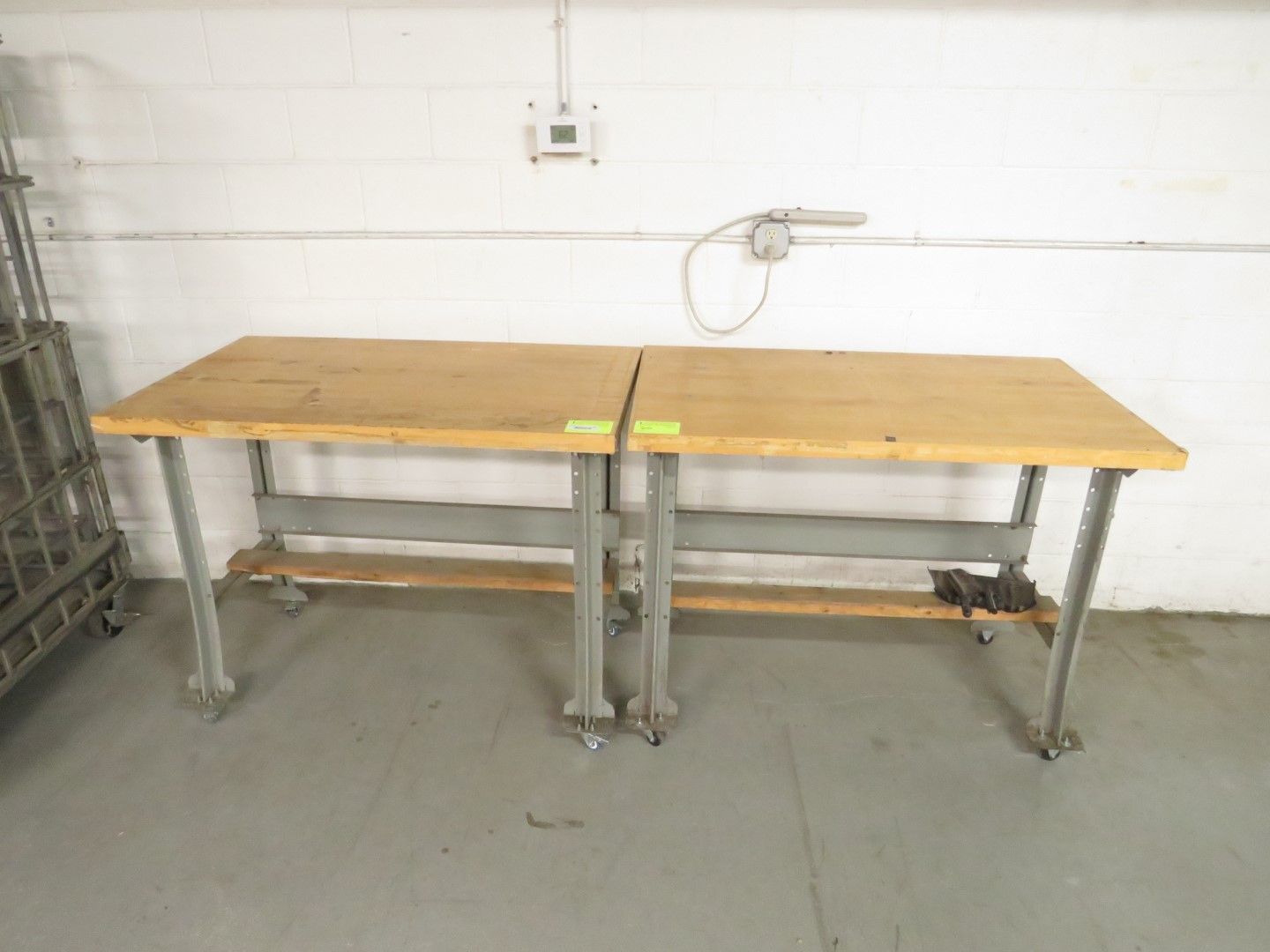 Two rectangular wooden work tables joined together, grey metal legs, casters, and a shelf.