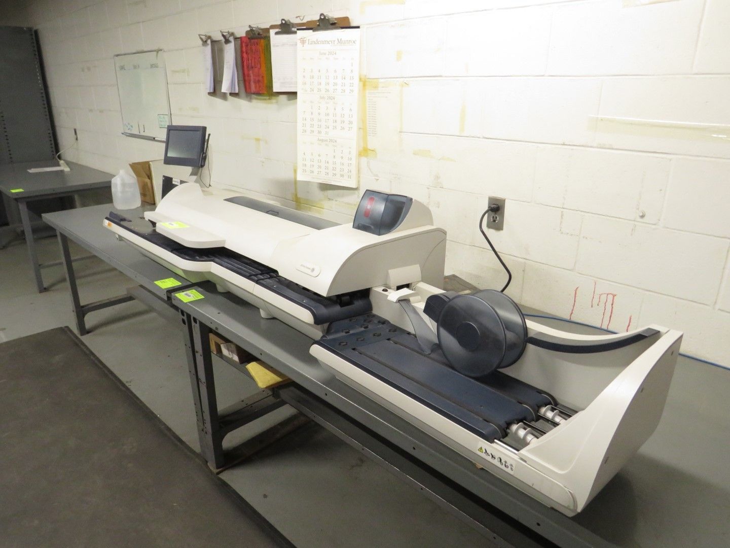A large white and gray mail processing machine on a gray table in a warehouse.