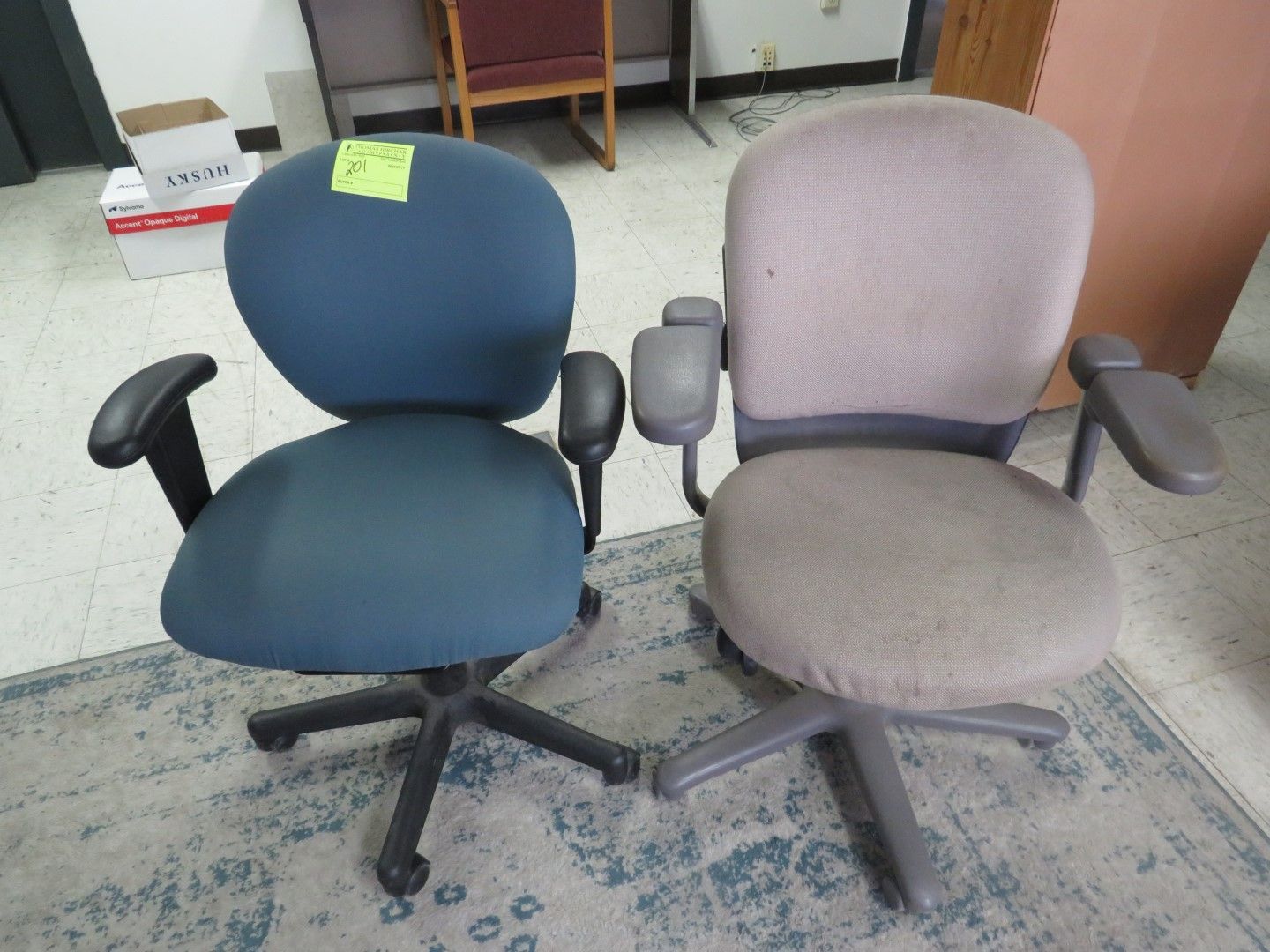 Two office chairs; one blue, one tan. Both have armrests and five-star bases.