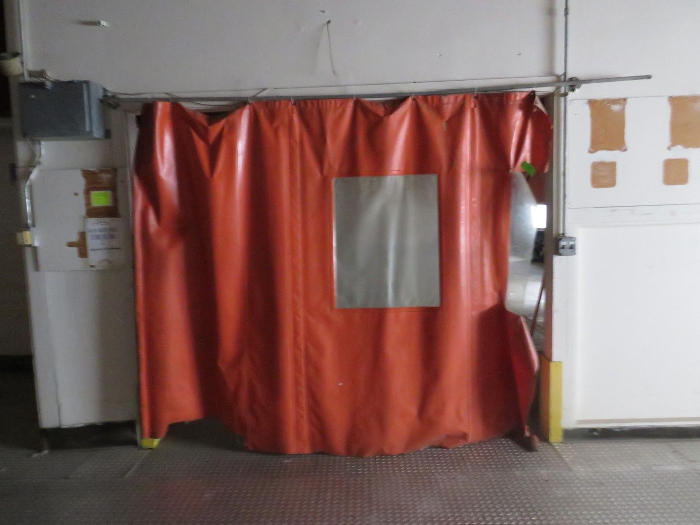 Orange curtain doorway with a clear window in an industrial setting.