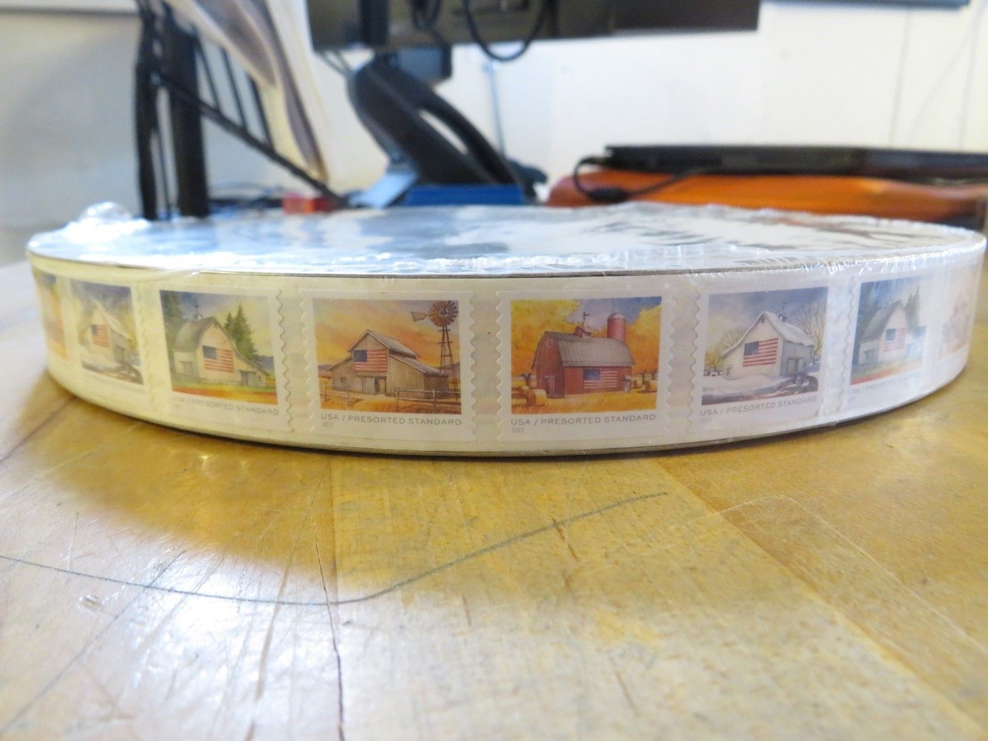 Roll of stamps featuring rural scenes, on a wood surface.