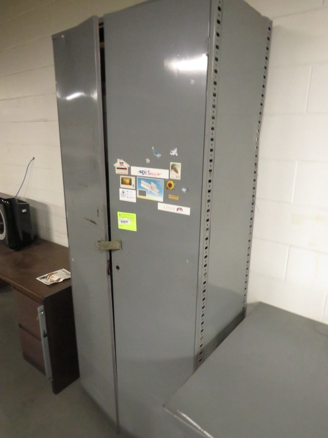 A tall, gray metal cabinet stands next to a wooden desk.