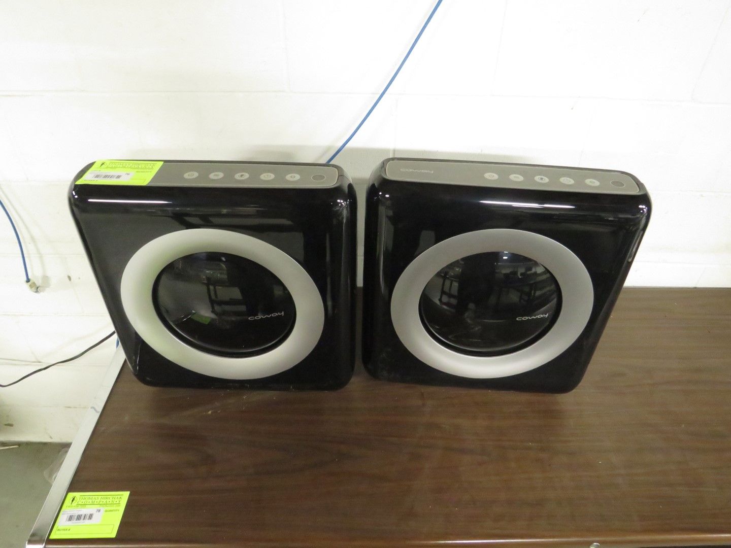 Two black square speakers with white circles, on a wooden surface.