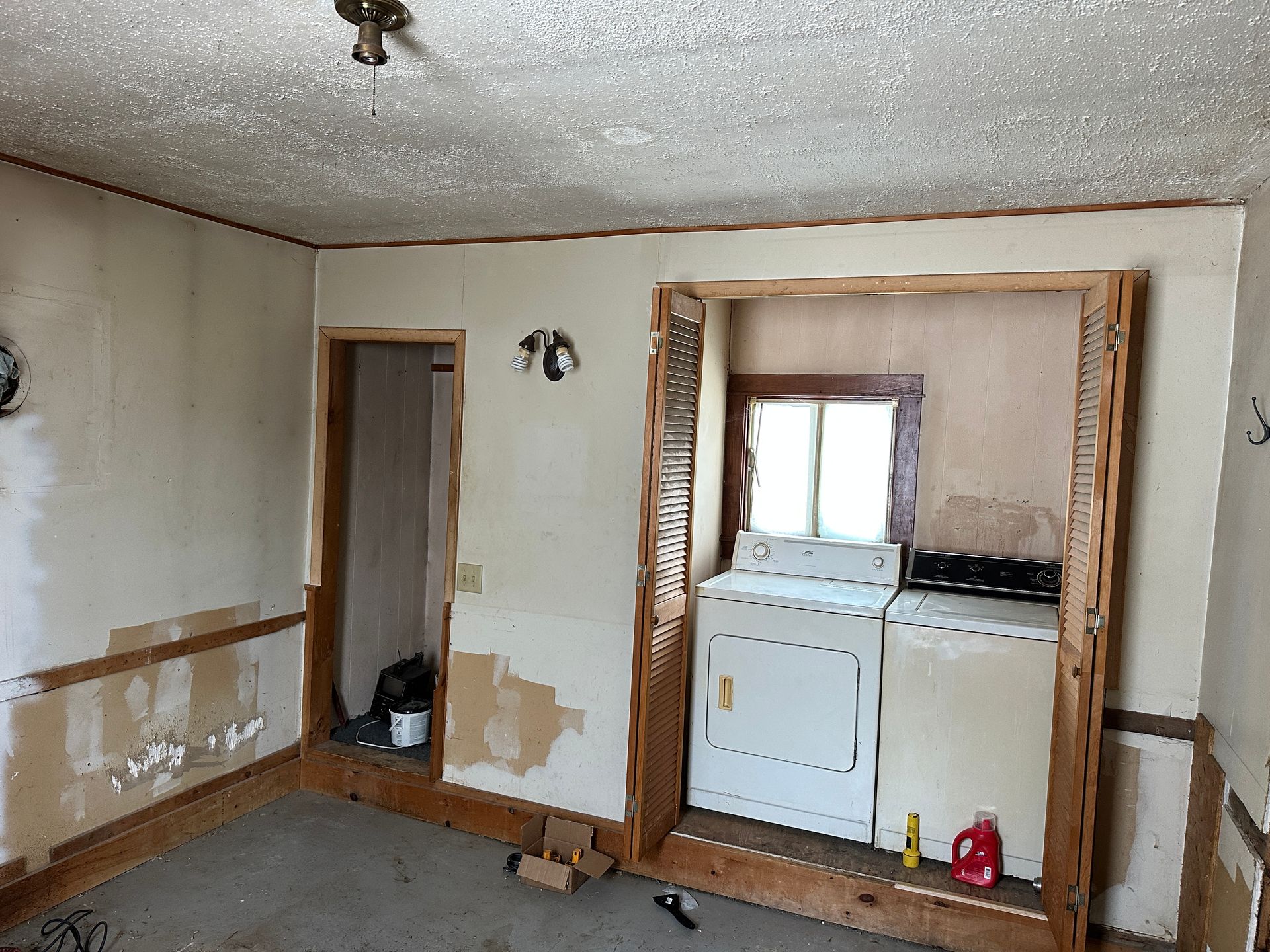 An interior room featuring plain walls, wood trim, a doorway, and a washer and dryer in an alcove.