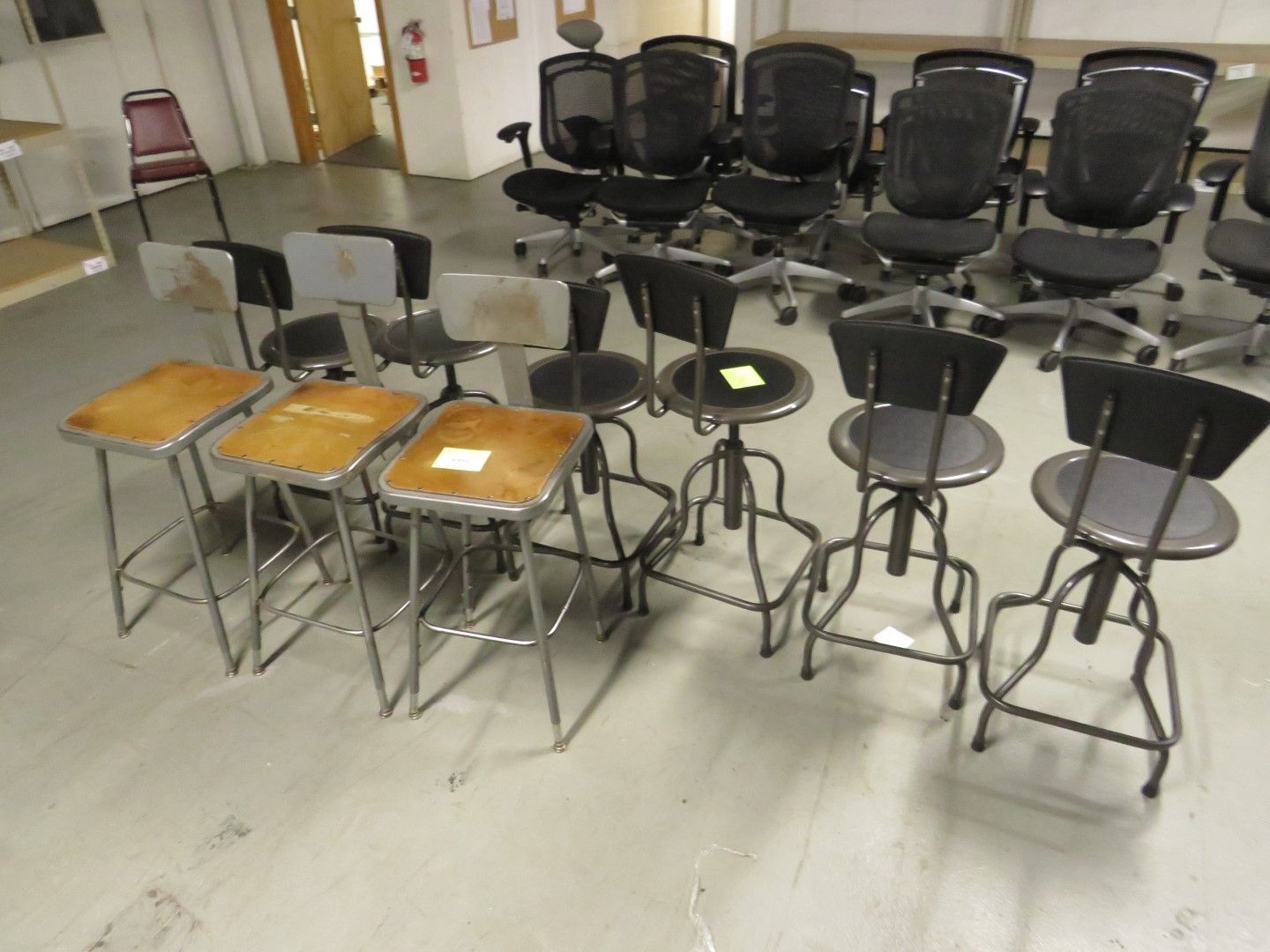 Rows of office chairs and stools on a warehouse floor.