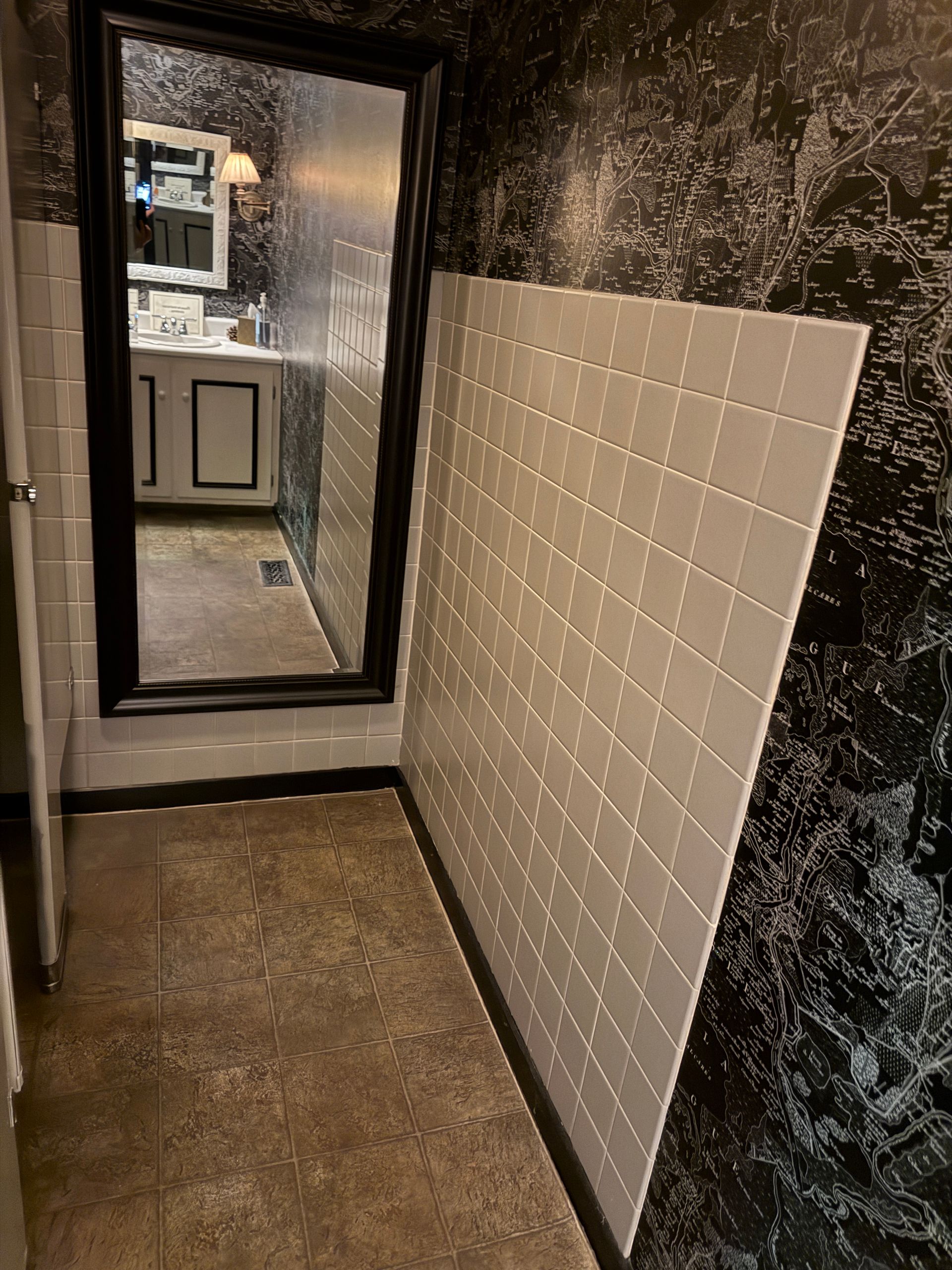Narrow hallway with dark walls, a mirror, and a large white tile panel