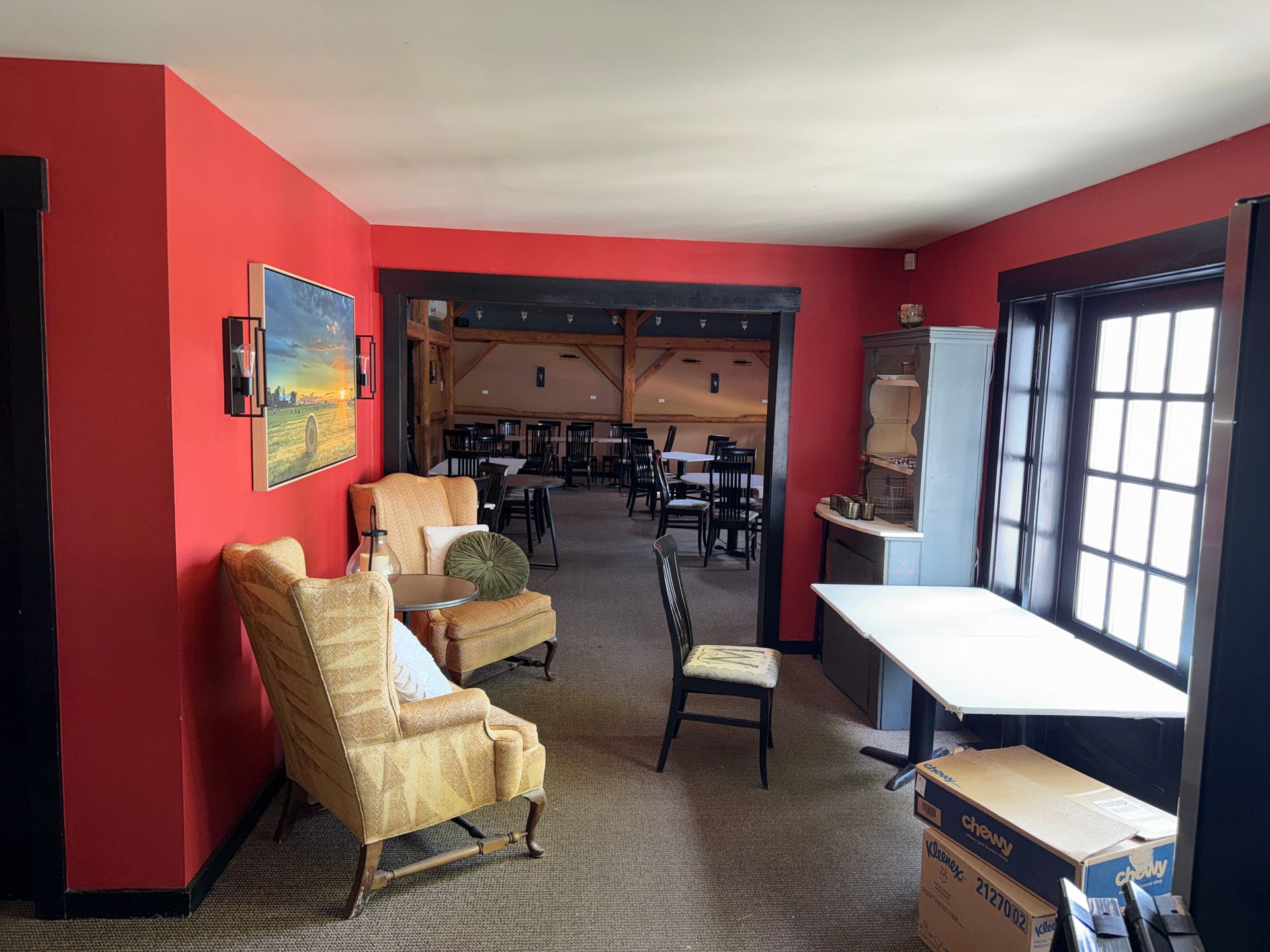 Bright red room with wicker chairs, table by windows, and a dining area in back
