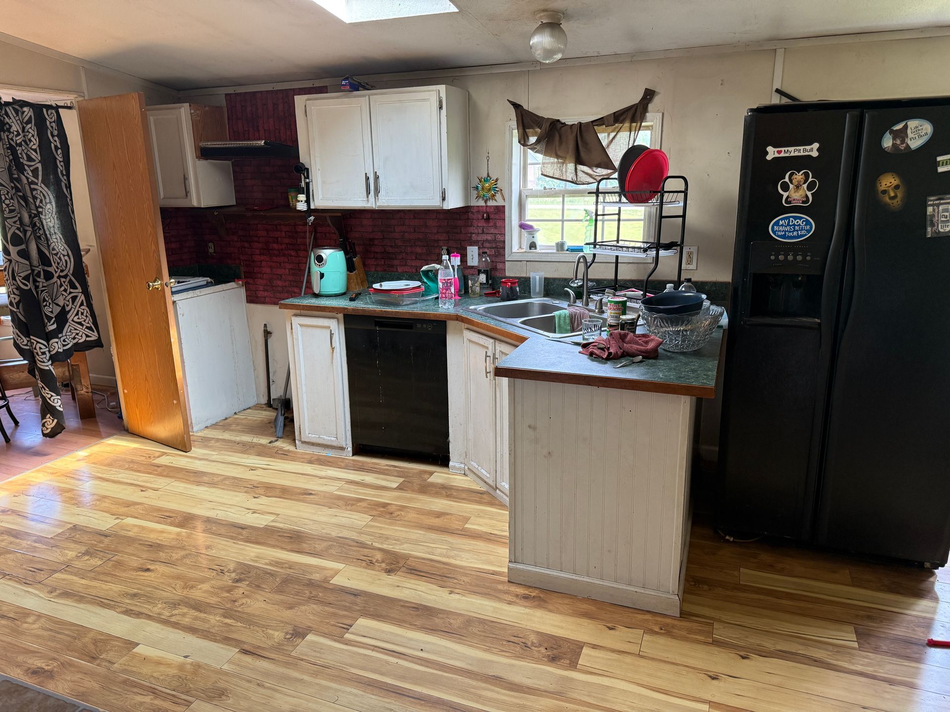 Bright kitchen with white cabinets, black appliances, and a small island by a window.