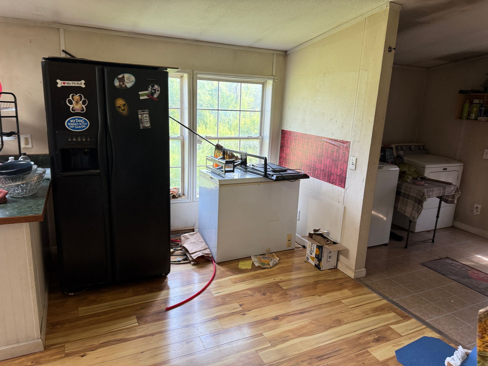Kitchen with black fridge, small sink cabinet, open door to sunny patio