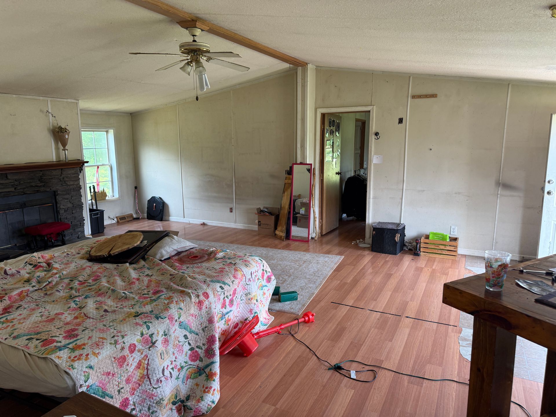 bedroom with floral bedspread, ceiling fan, open doorway