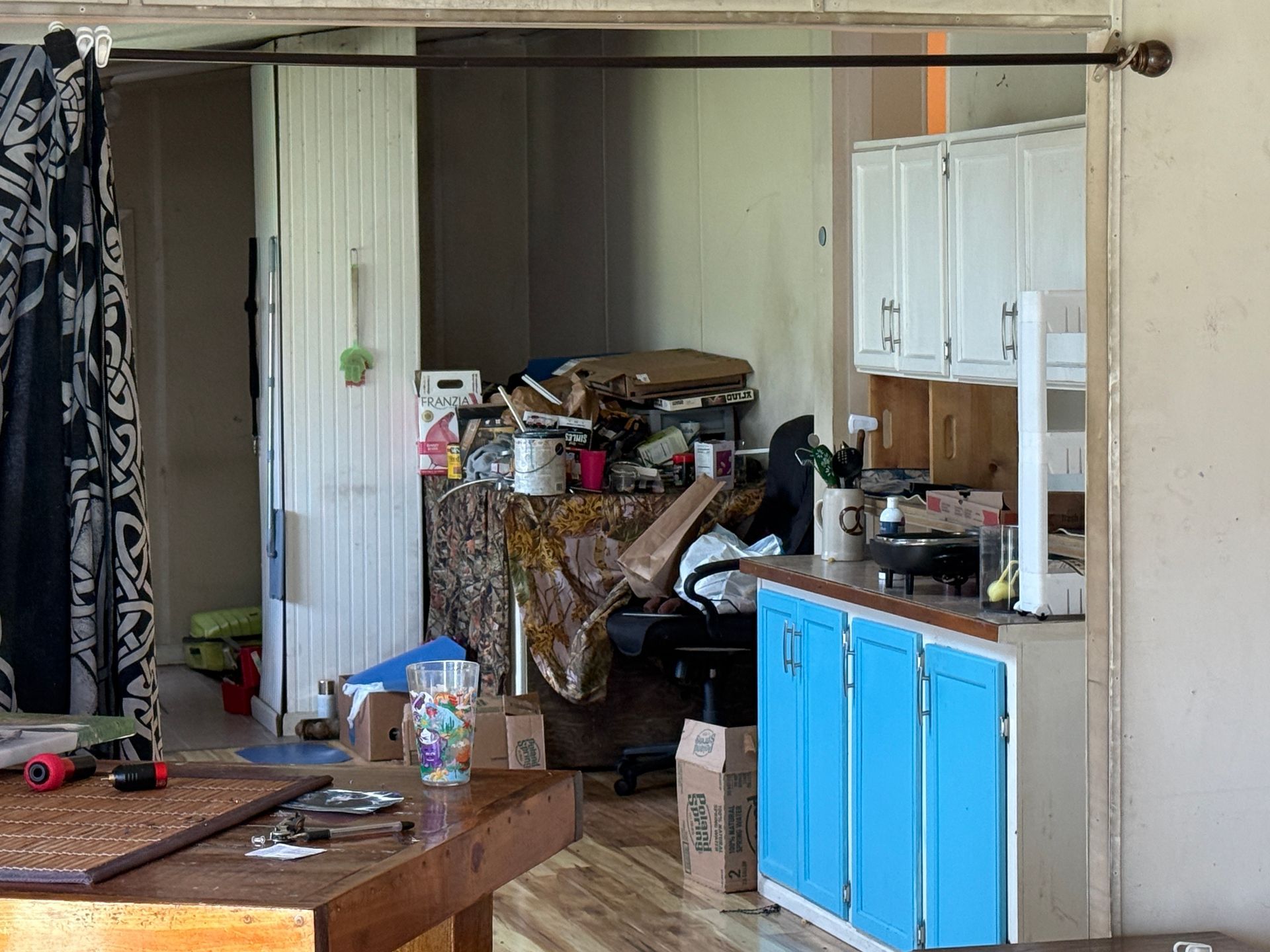 garage with stacked boxes, tools, a blue cabinet, and a white door under an open beam ceiling