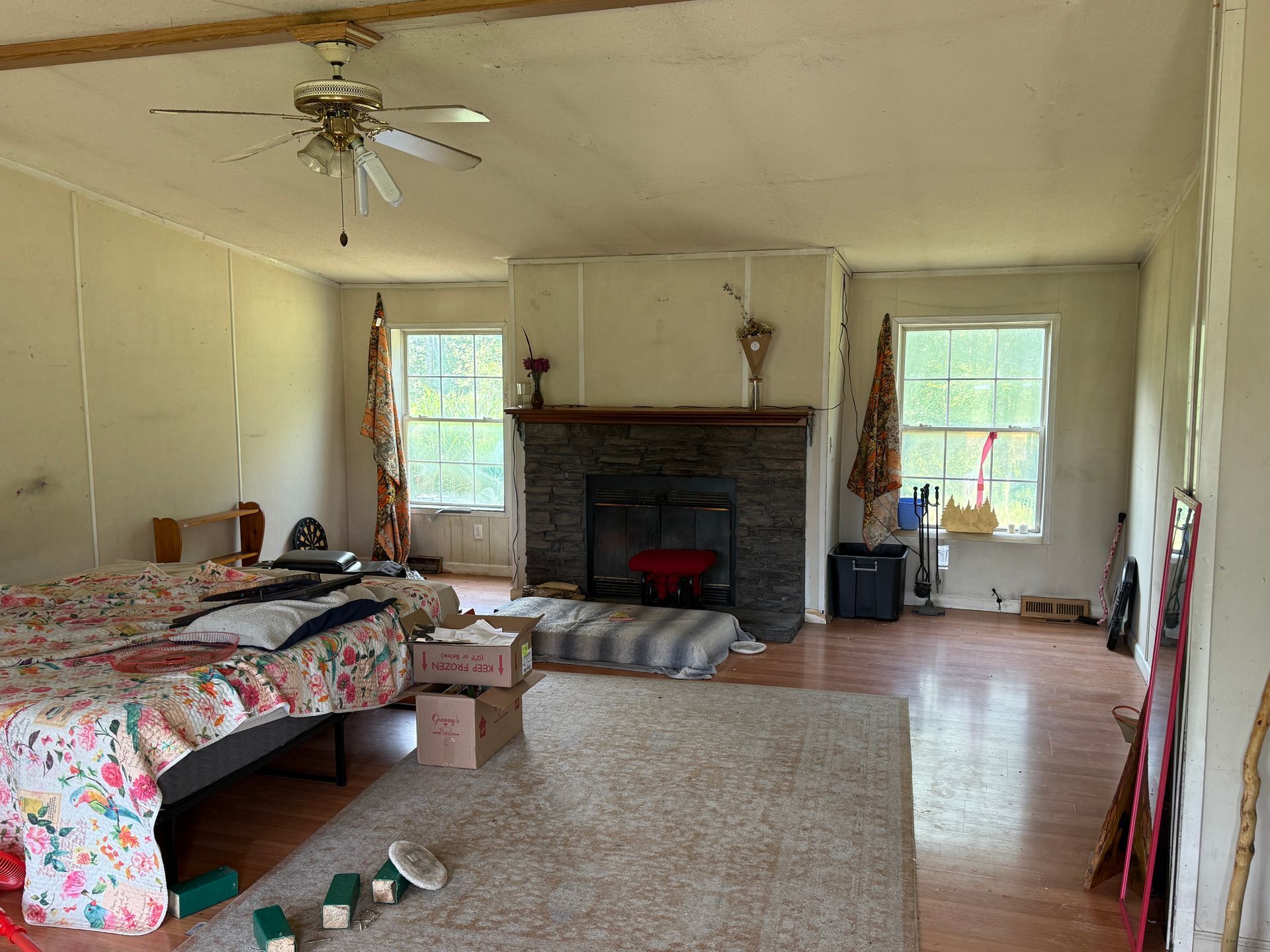 Spacious bedroom with two beds, a fireplace, windows, and light wood floors