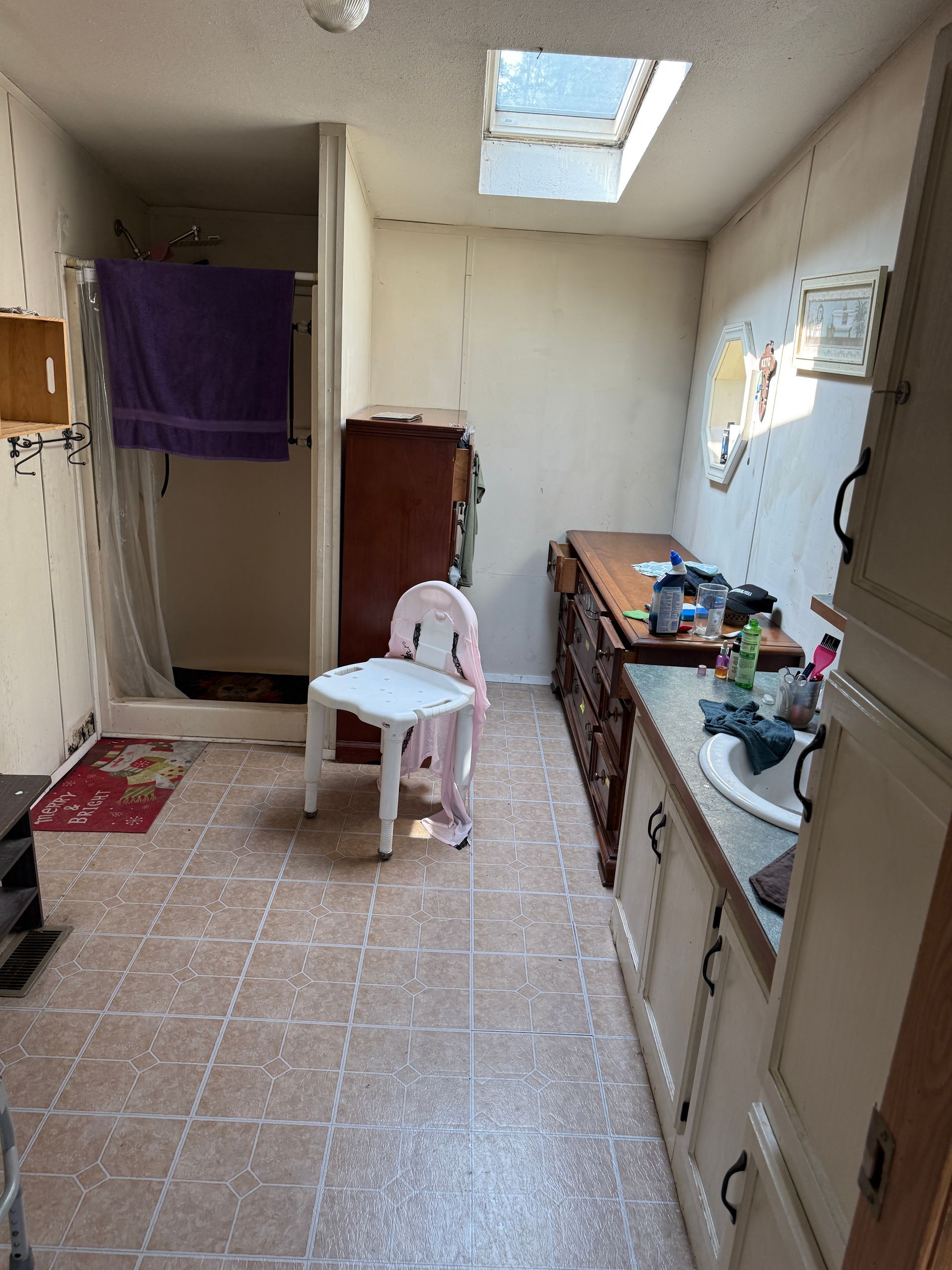 Narrow kitchen with beige tile floor, skylight, sink counter