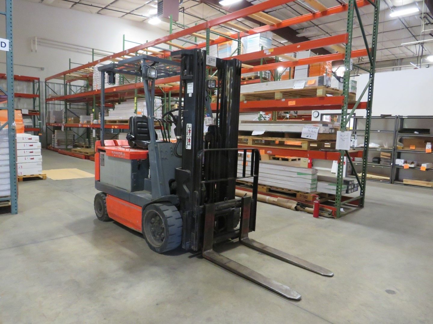Forklift in a warehouse with shelves of building materials.