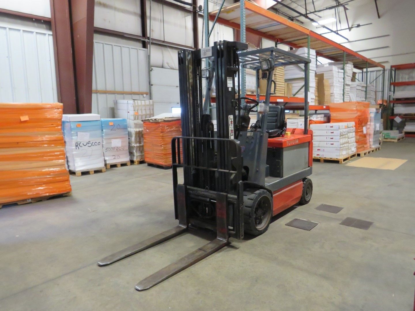 Forklift in a warehouse with pallets of materials.
