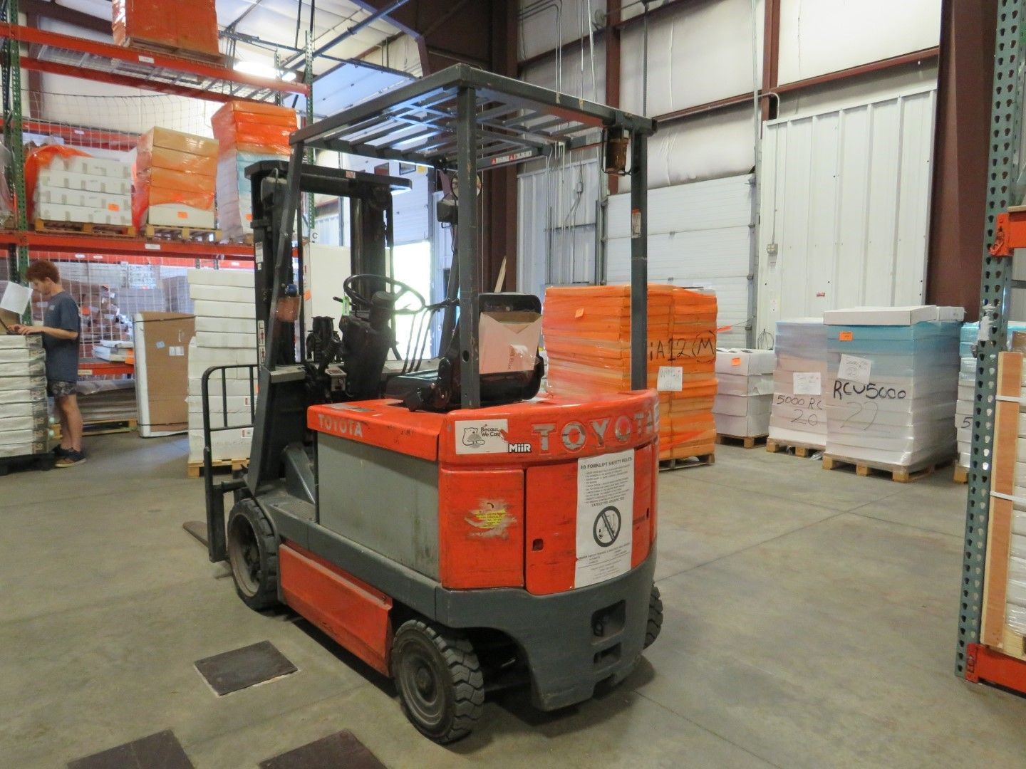 Forklift in a warehouse with stacked pallets.