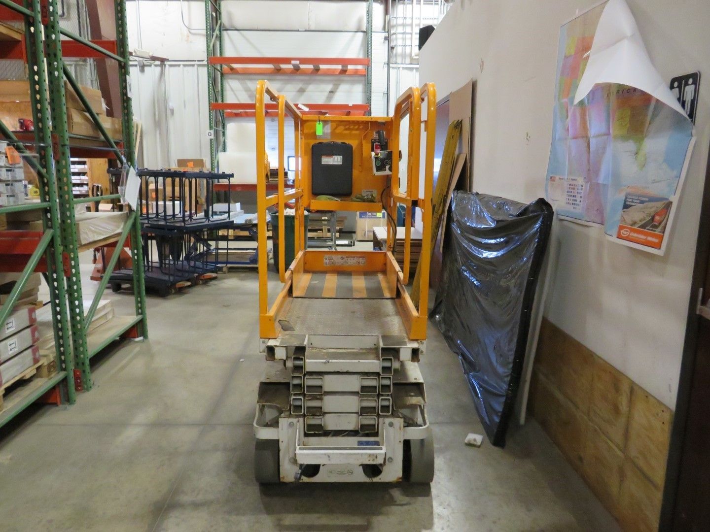 An yellow industrial lift in a warehouse aisle.