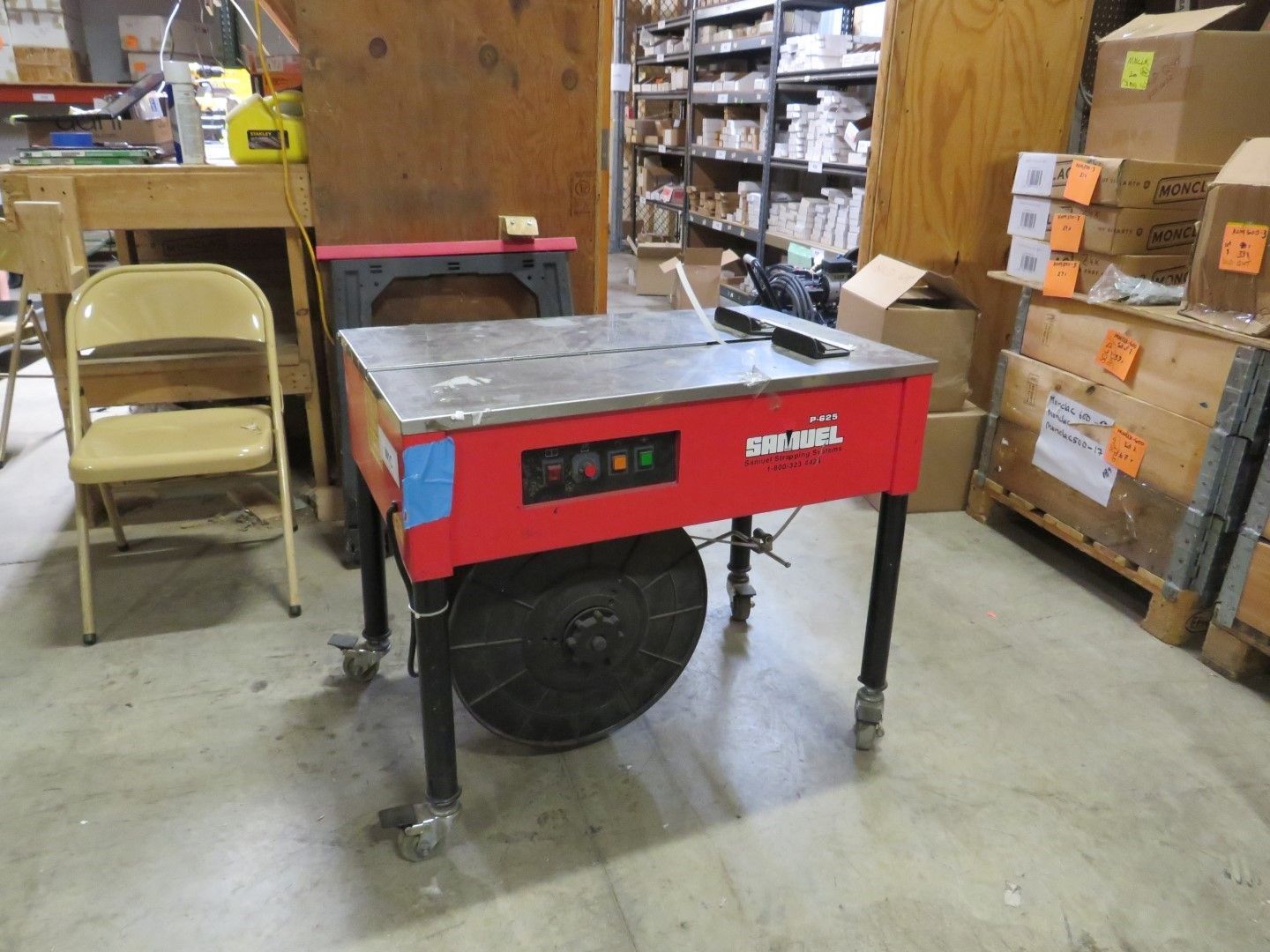 Red metal welding table on wheels in a warehouse setting.