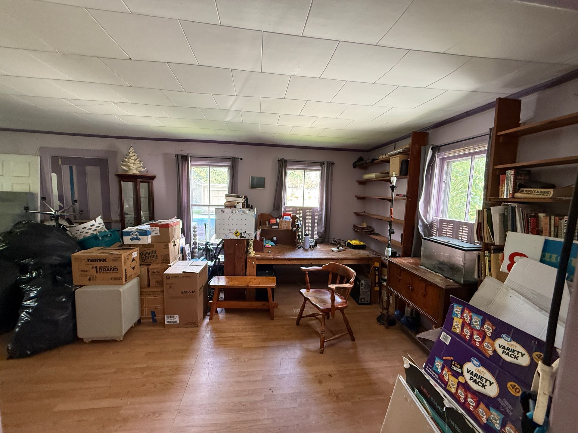 living room with boxes, shelves, desk, and wooden floor in a bright space