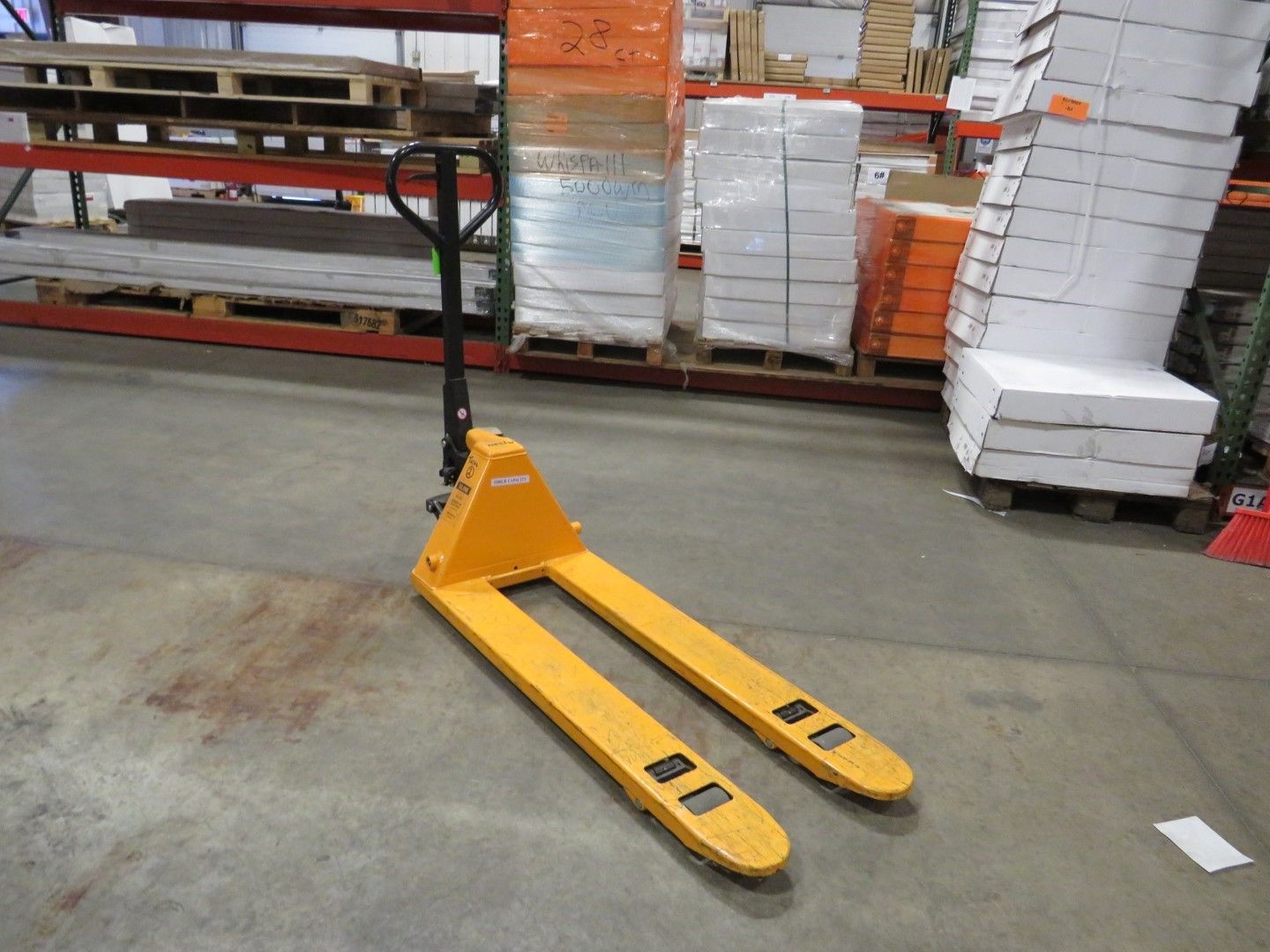 Yellow pallet jack in a warehouse.