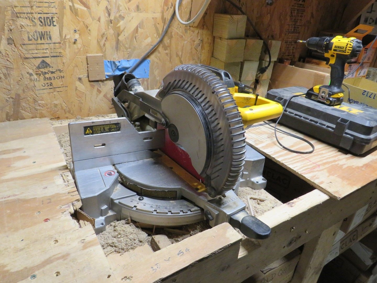 A yellow and silver miter saw on a wooden workbench.