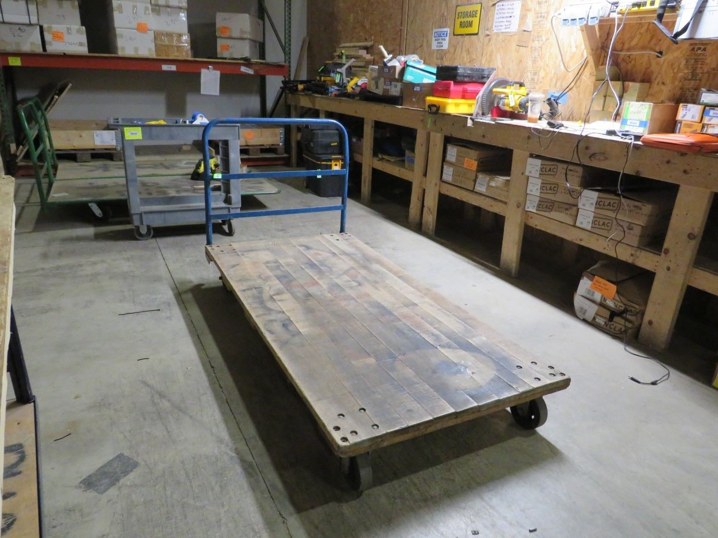 Warehouse with a large wooden cart in the foreground. Another cart and work bench are visible in the background.