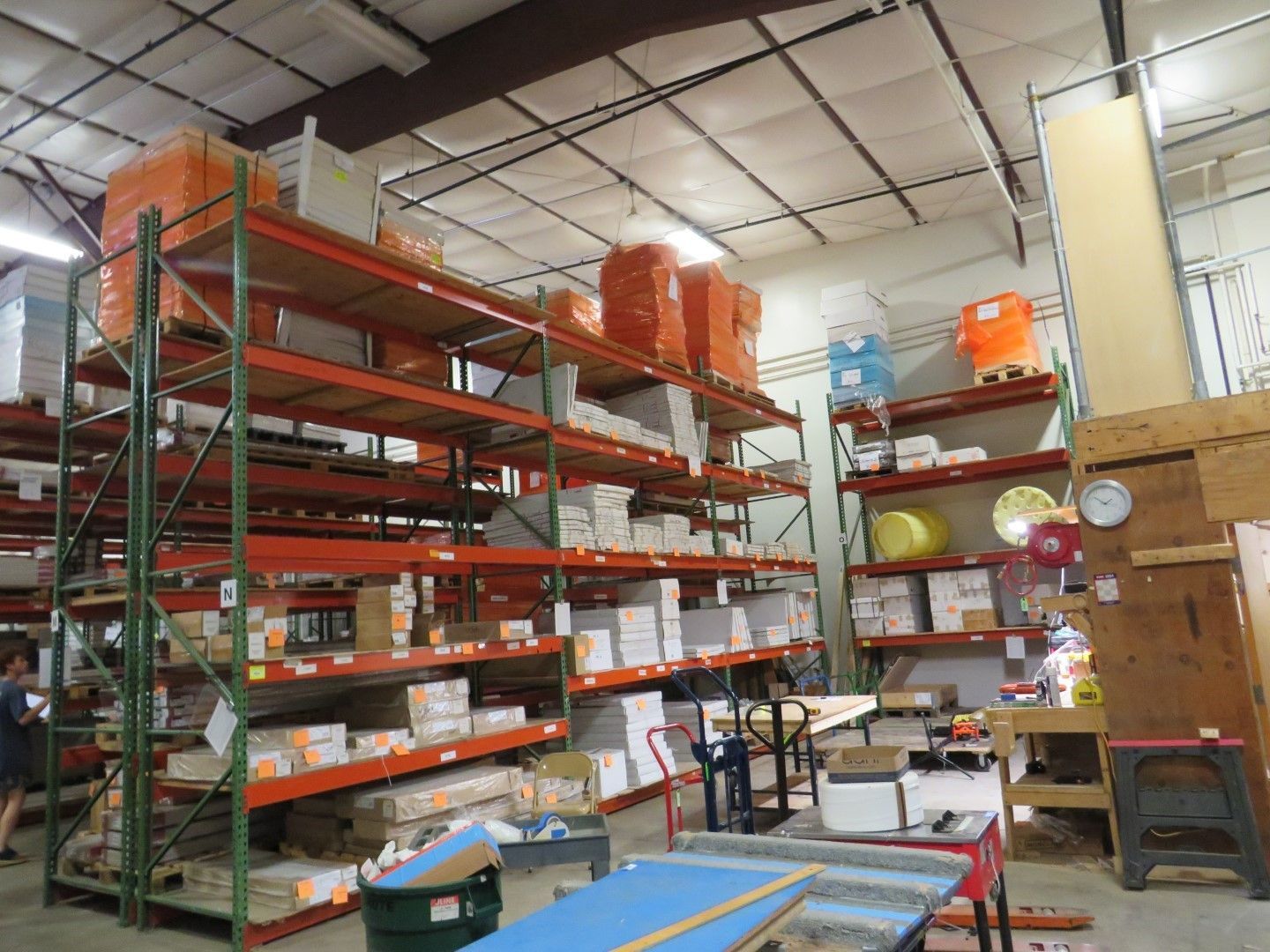 Warehouse interior with shelving, containing stacked boxes and supplies.