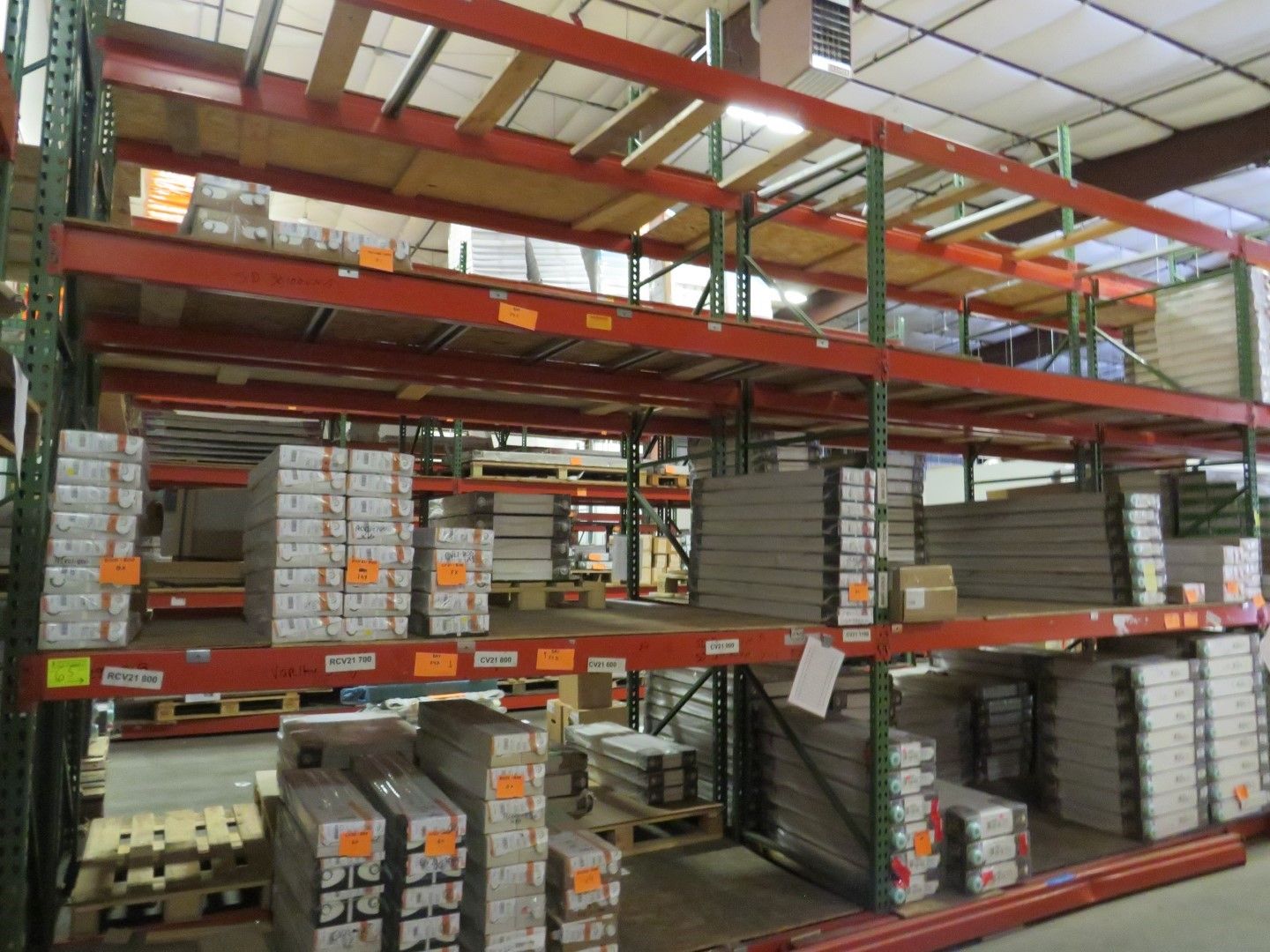 Warehouse shelving stacked with packages of various products. Red and green metal supports.