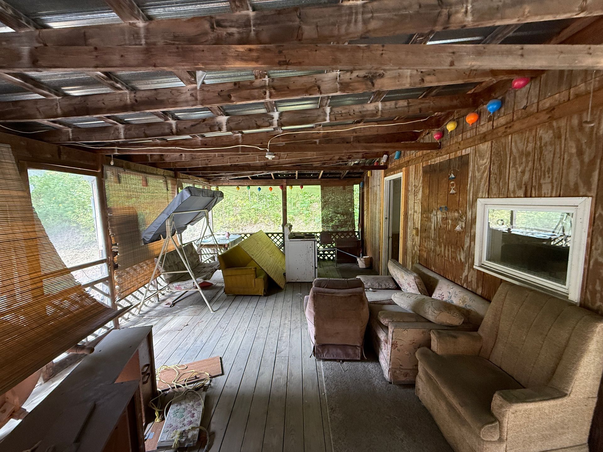 Rustic screened porch with wicker chairs, a couch