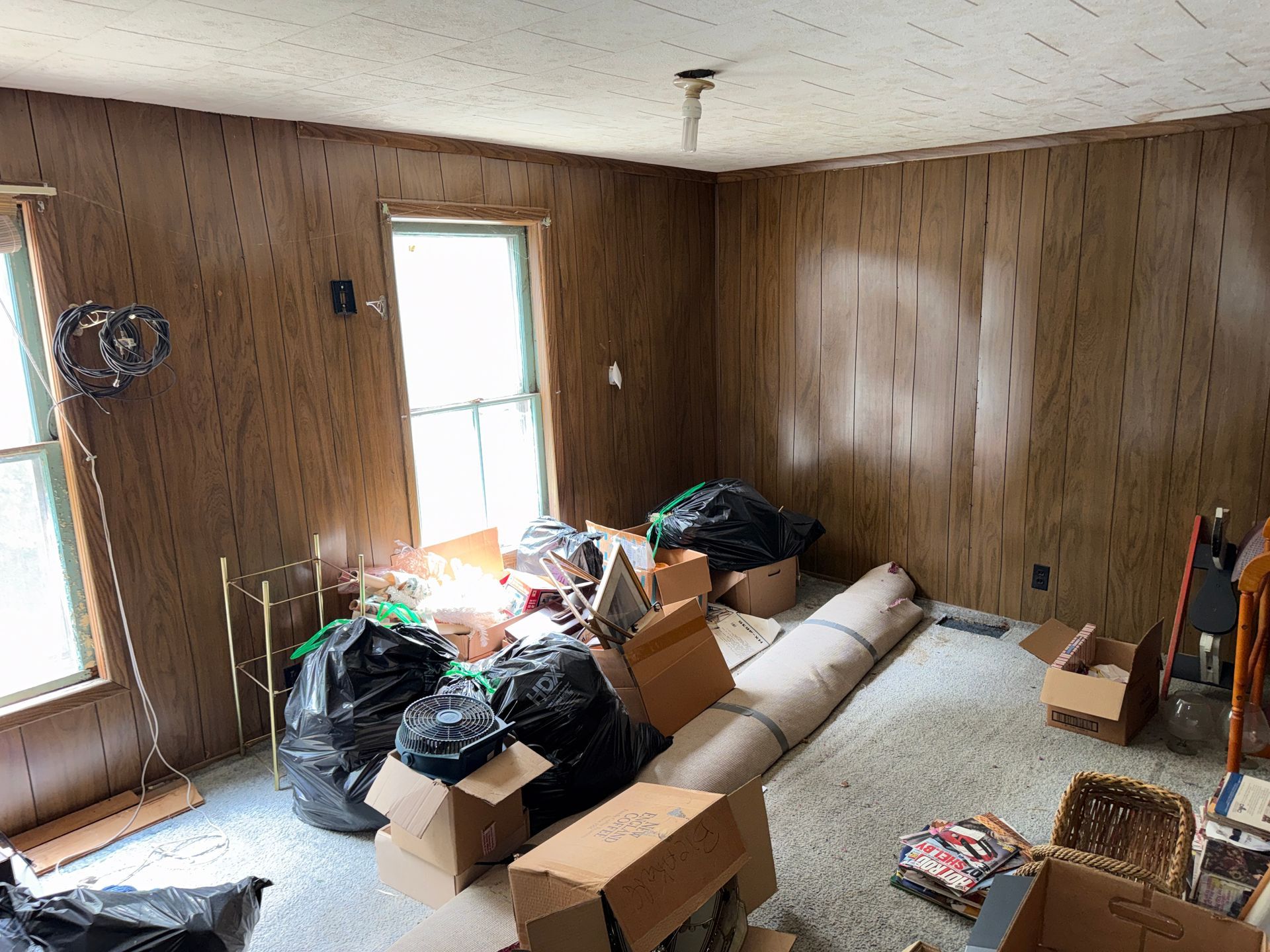 Small wood-paneled room with two tall windows.