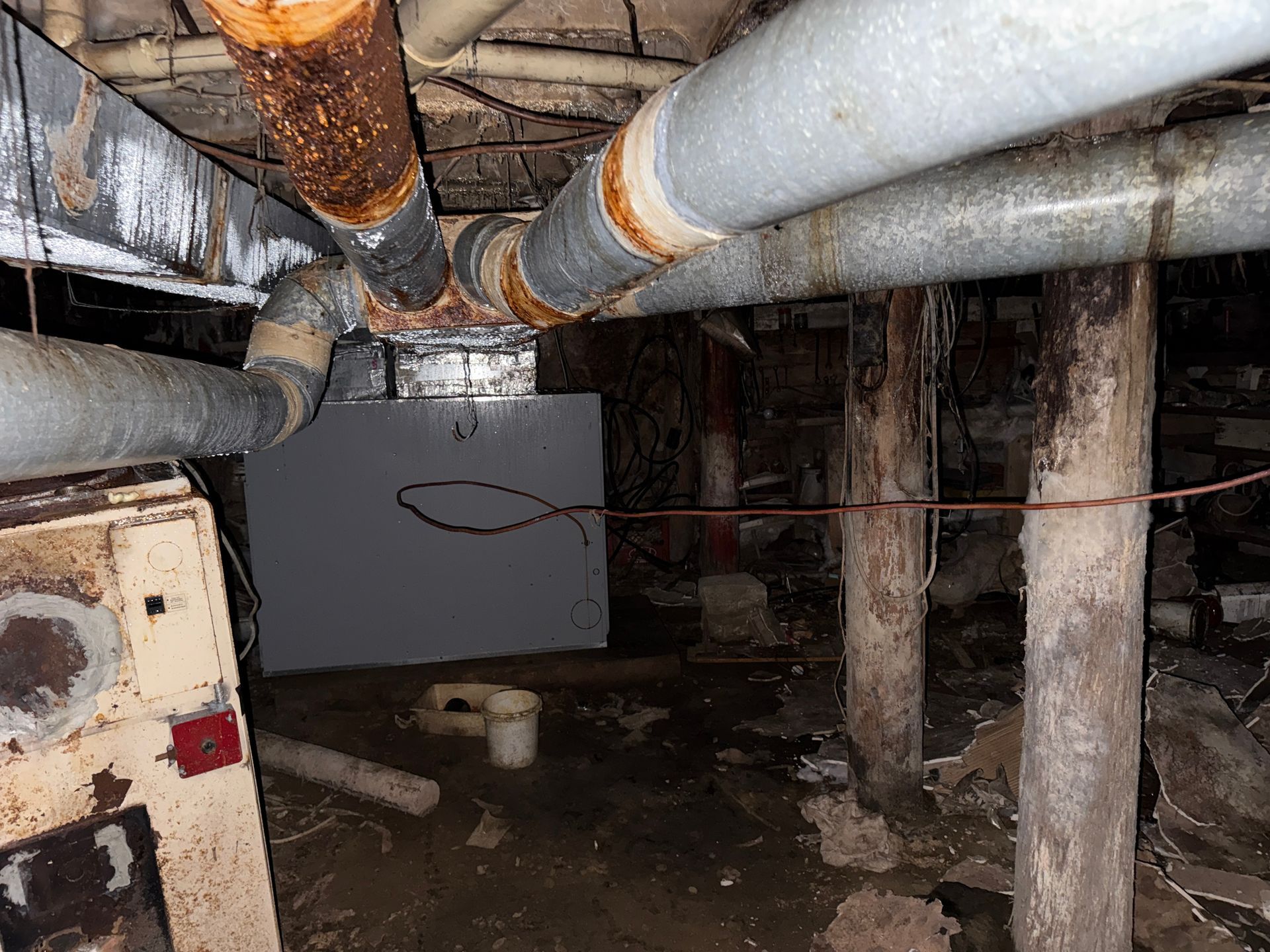Crawl space with exposed pipes, support posts