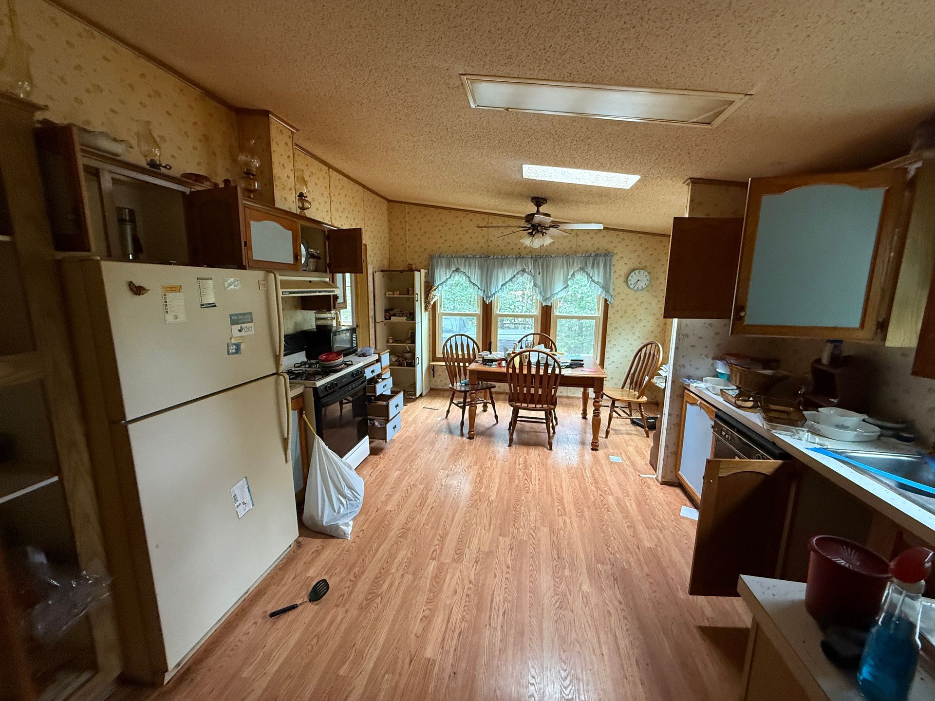 kitchen with wood floors, white fridge, sink, and dining table by a bright window.