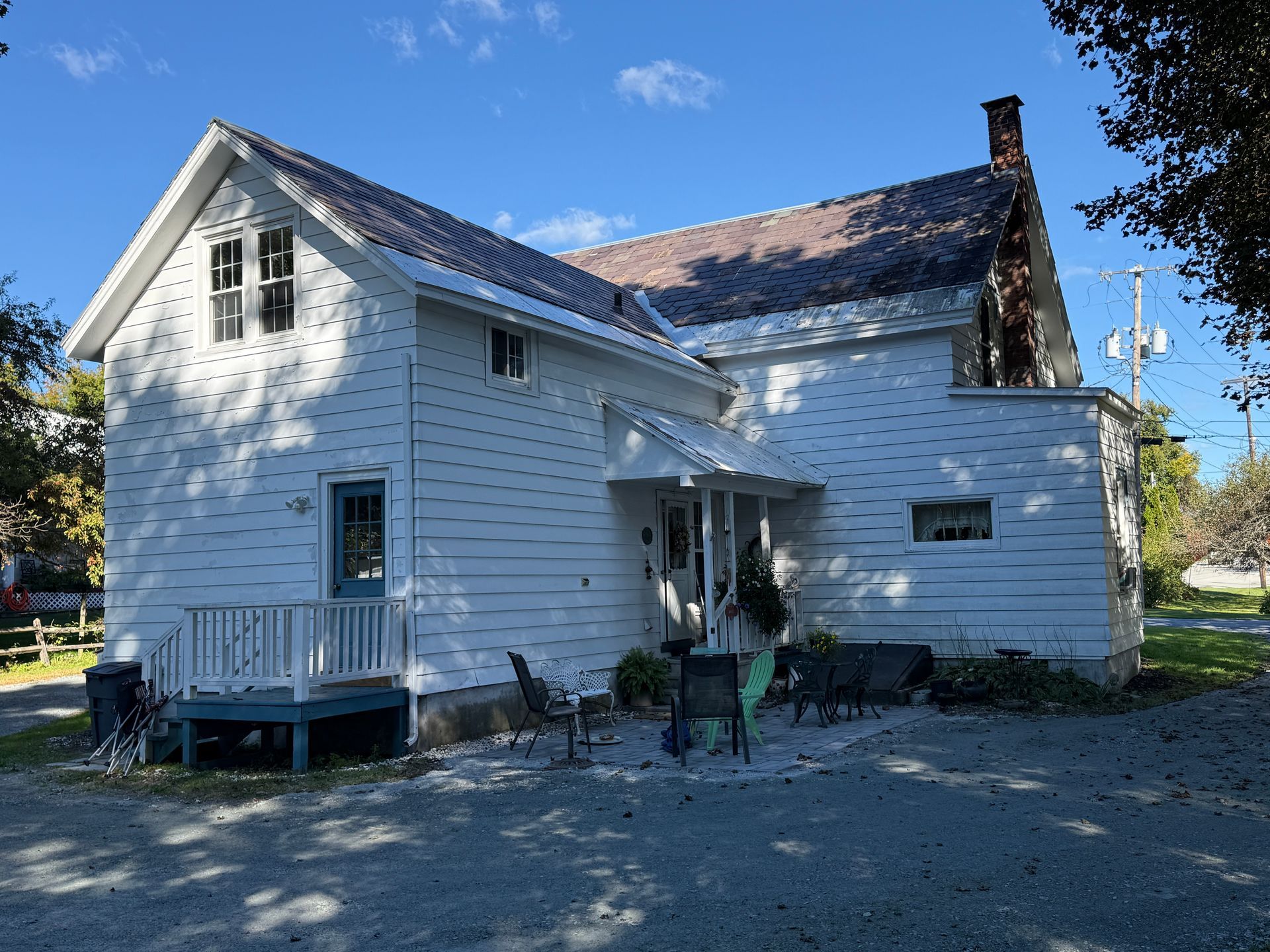 White house with a small porch and chimney under a blue sky