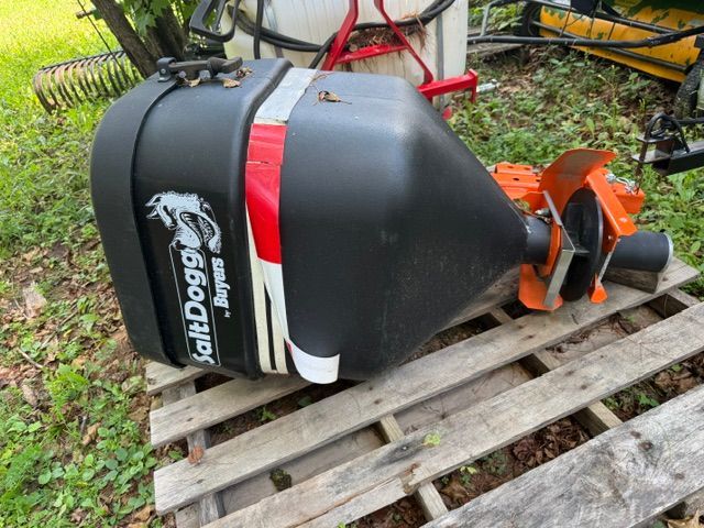 Black-and-red BinDogg farm implement on a wooden pallet outdoors