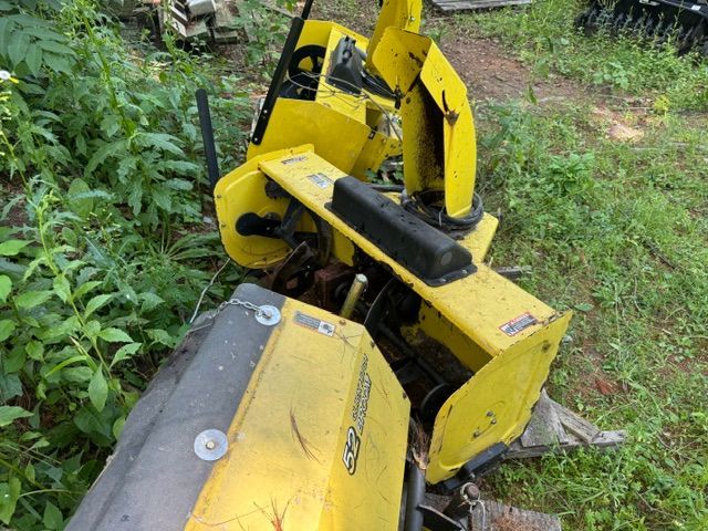 Yellow industrial machine or excavator arm in overgrown greenery outdoors