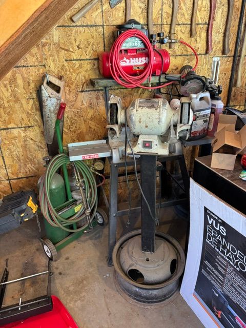 industrial machine with red hose reel and coiled green hose in a workshop garage.
