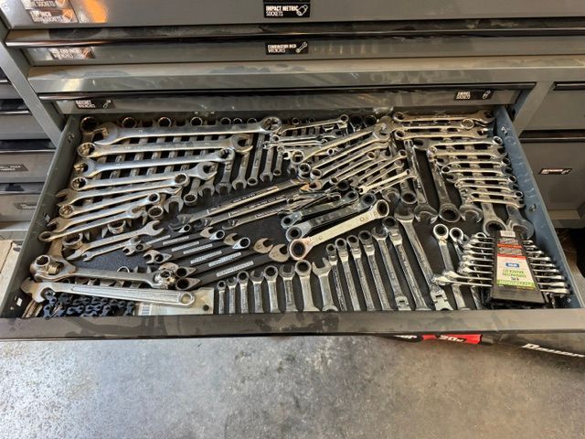 Drawer full of assorted wrenches and hand tools in a metal toolbox
