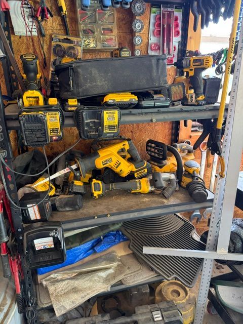 workshop shelf packed with yellow power tools, batteries, and hand tools.