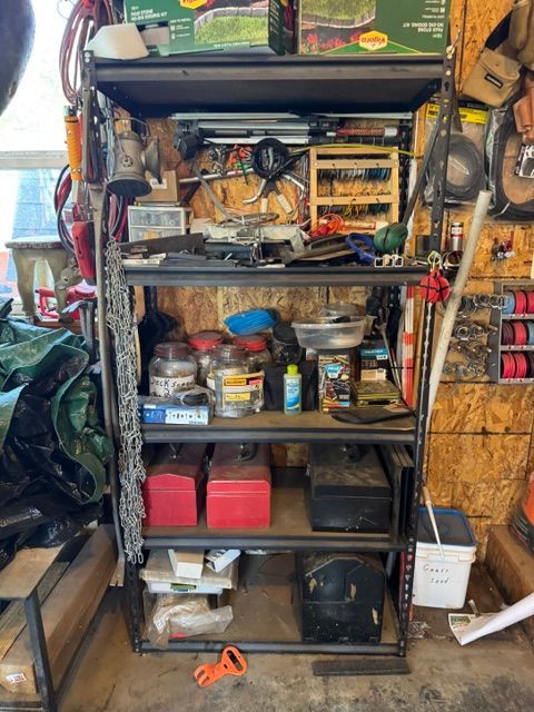 Metal shelving unit packed with tools, cans, bins, and supplies