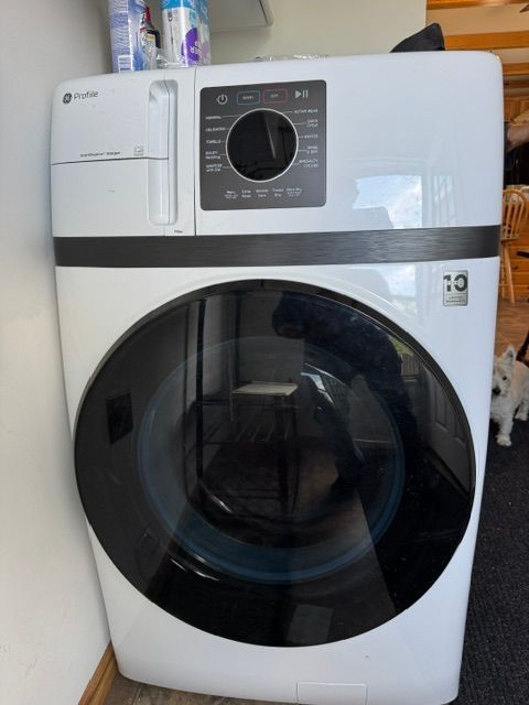 White front-loading washing machine with a dark round door and control panel at the top.