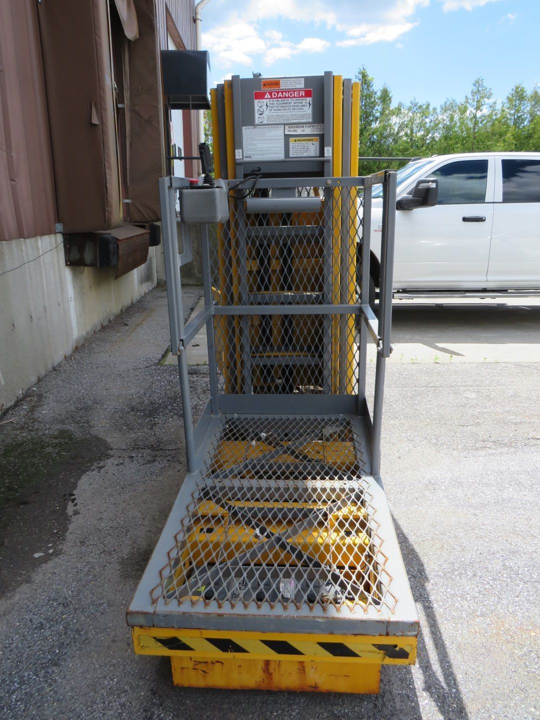 Yellow and gray industrial lift next to a loading dock.