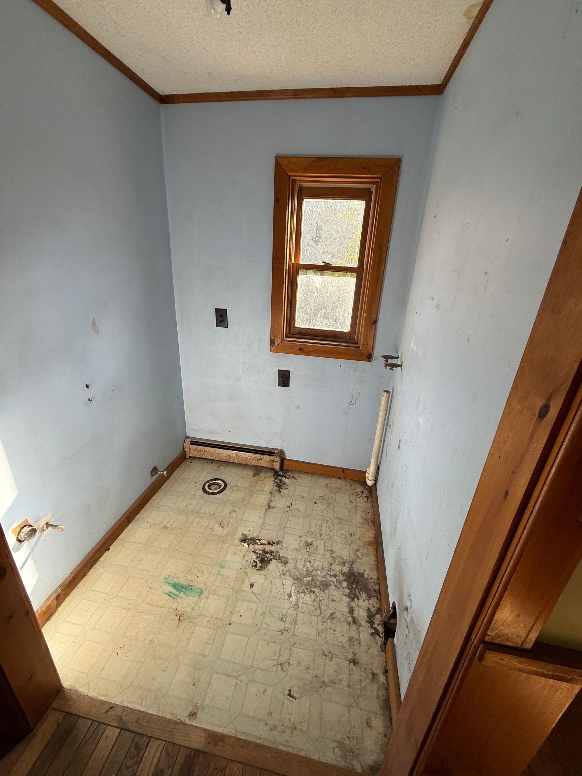 Small empty room with white walls, tiled floor, and a single window