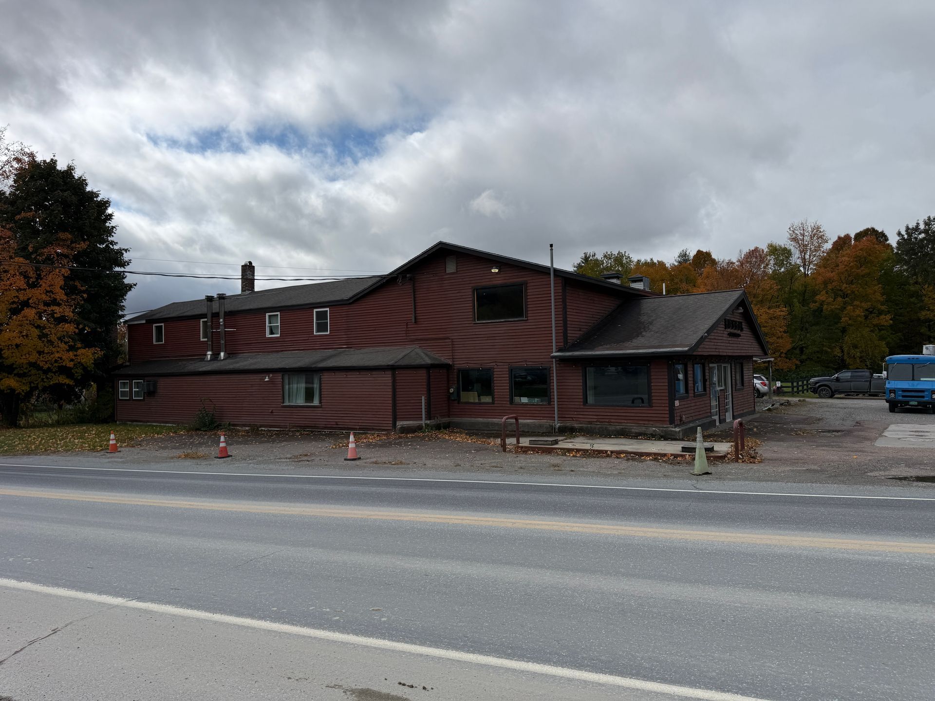 Red wooden roadside building with a parking lot under cloudy autumn sky