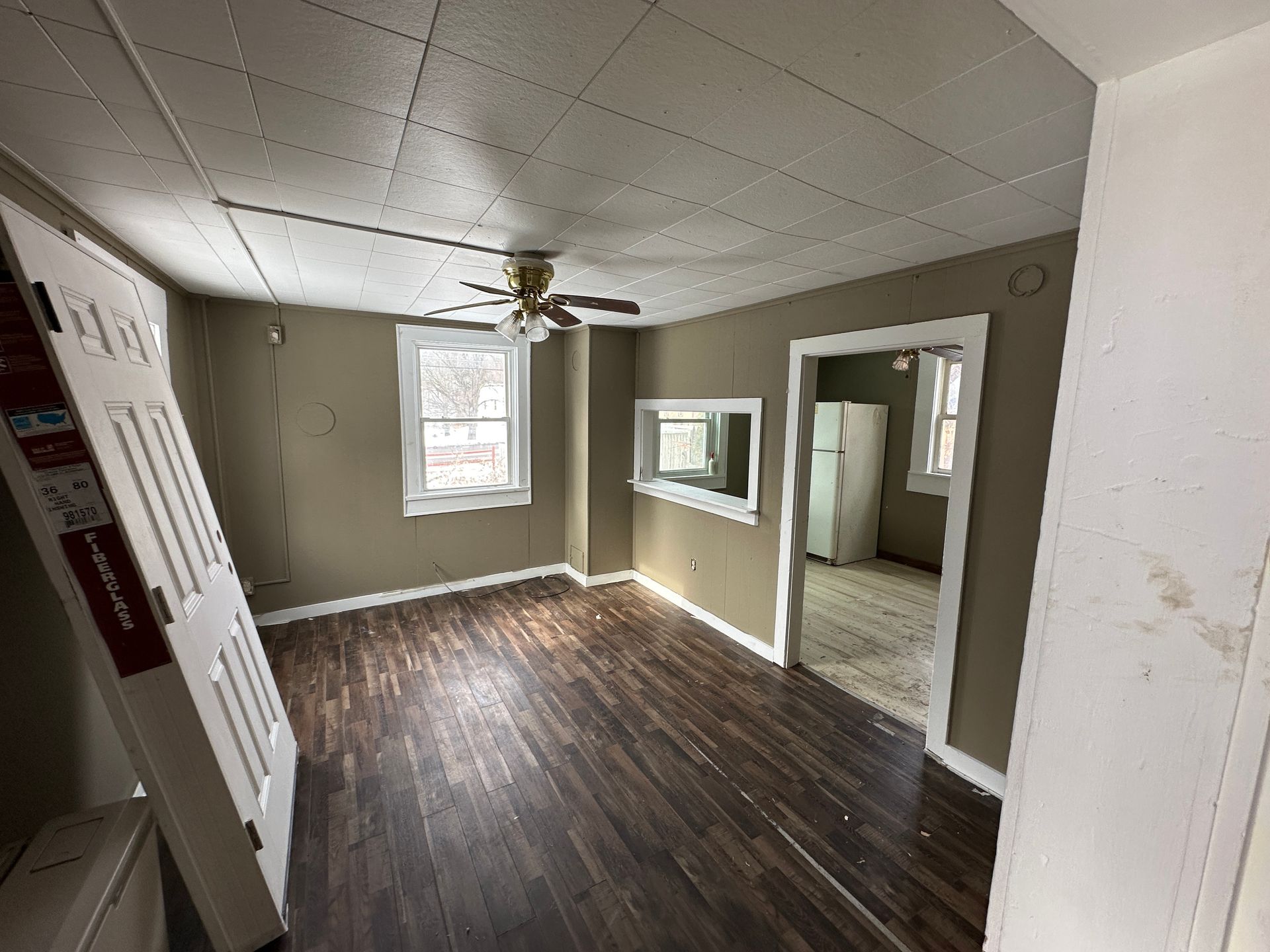 Interior view of a room with dark wood flooring, tan walls, a white ceiling, and a doorway.