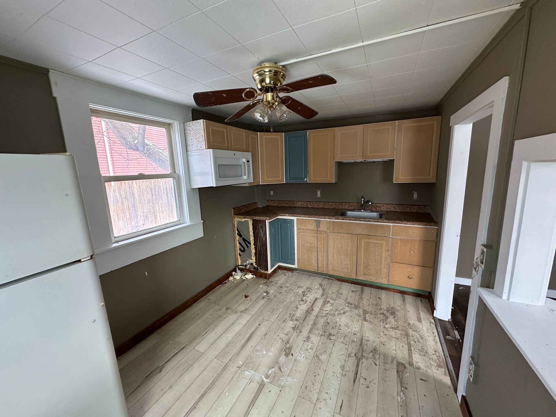 Kitchen with light wood cabinets, gray walls, and a window.