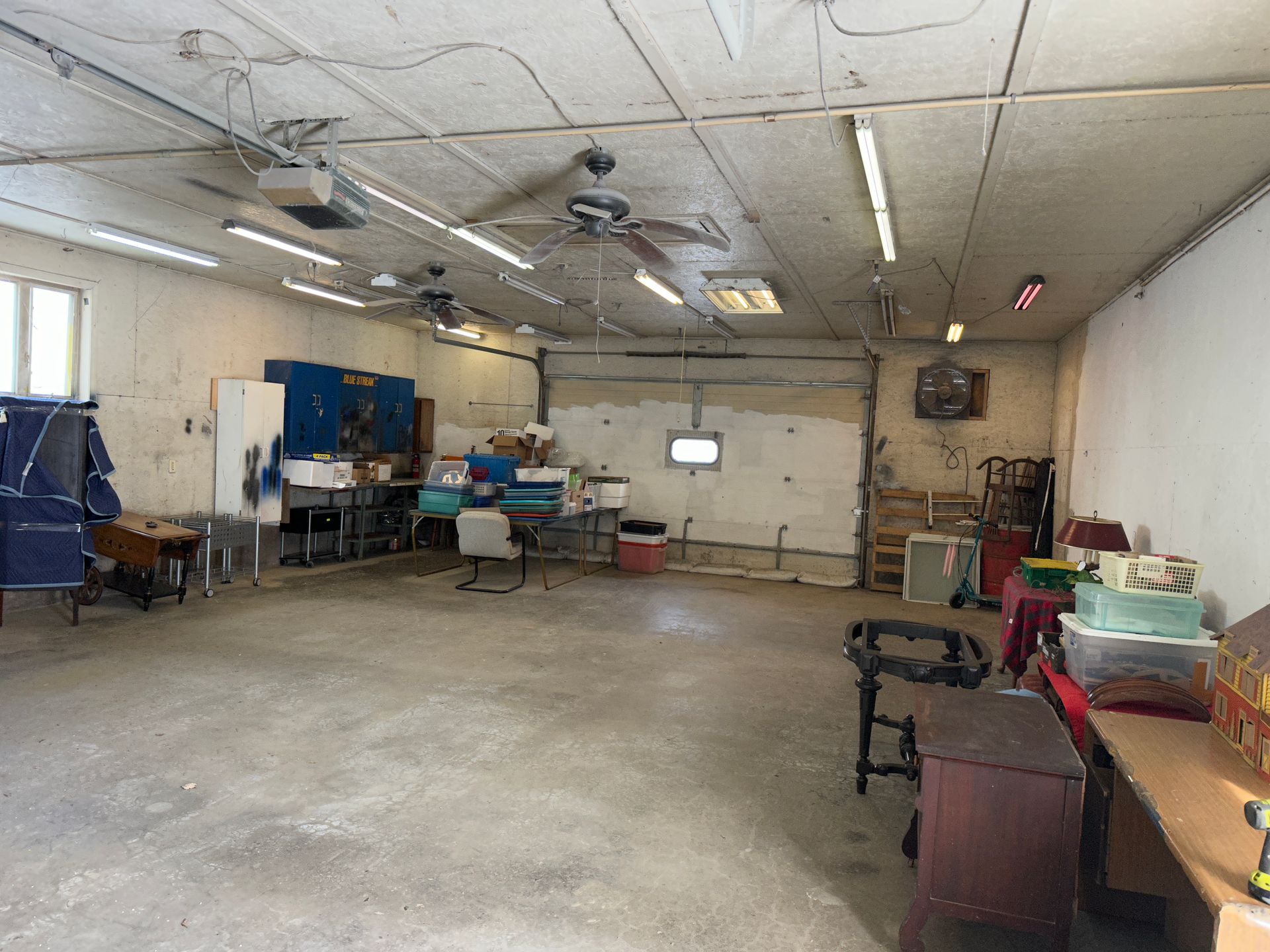 Workshop interior with various tools, tables, and ceiling fans.