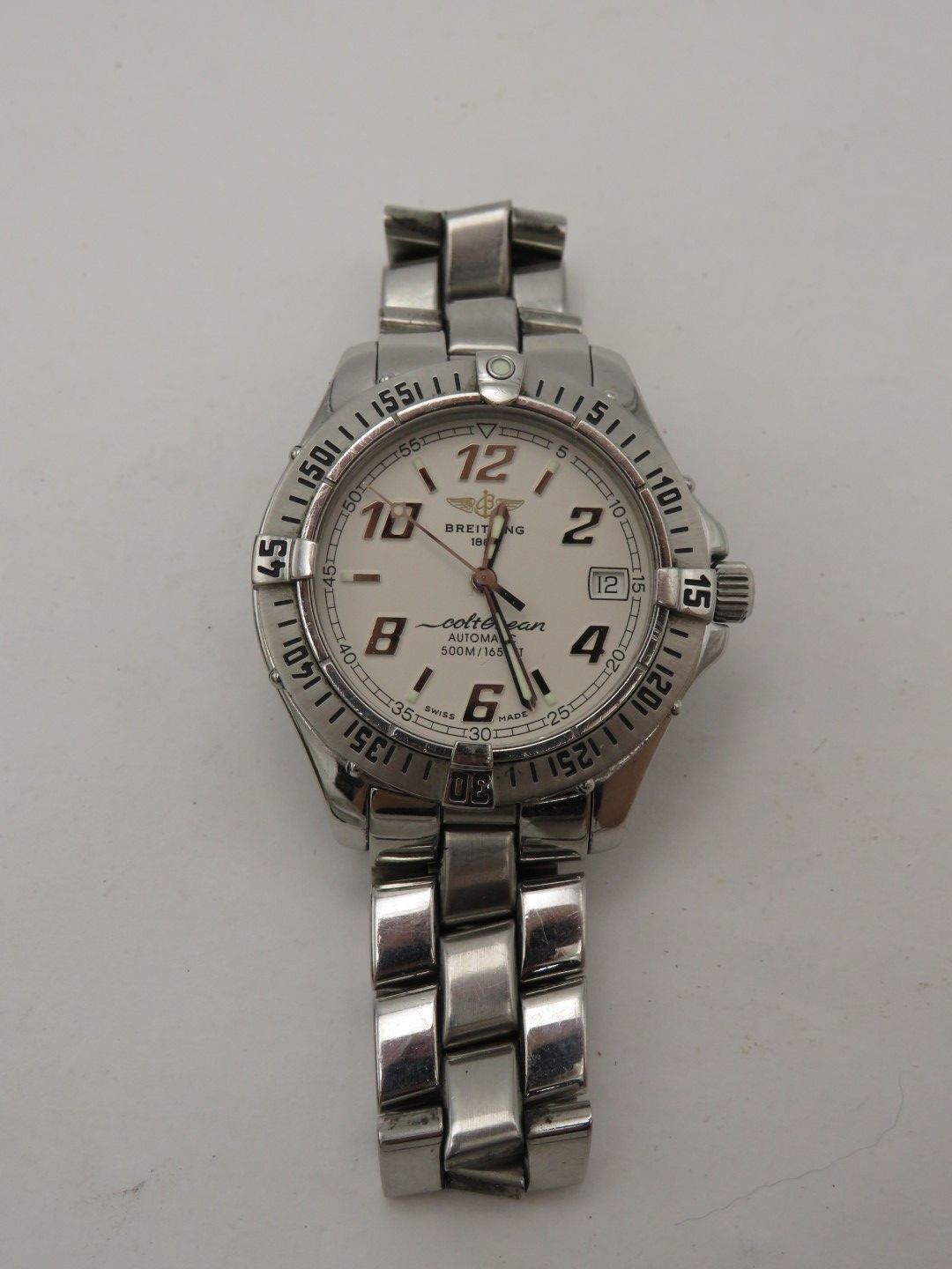 Silver wristwatch with white face and black numerals on a white background.