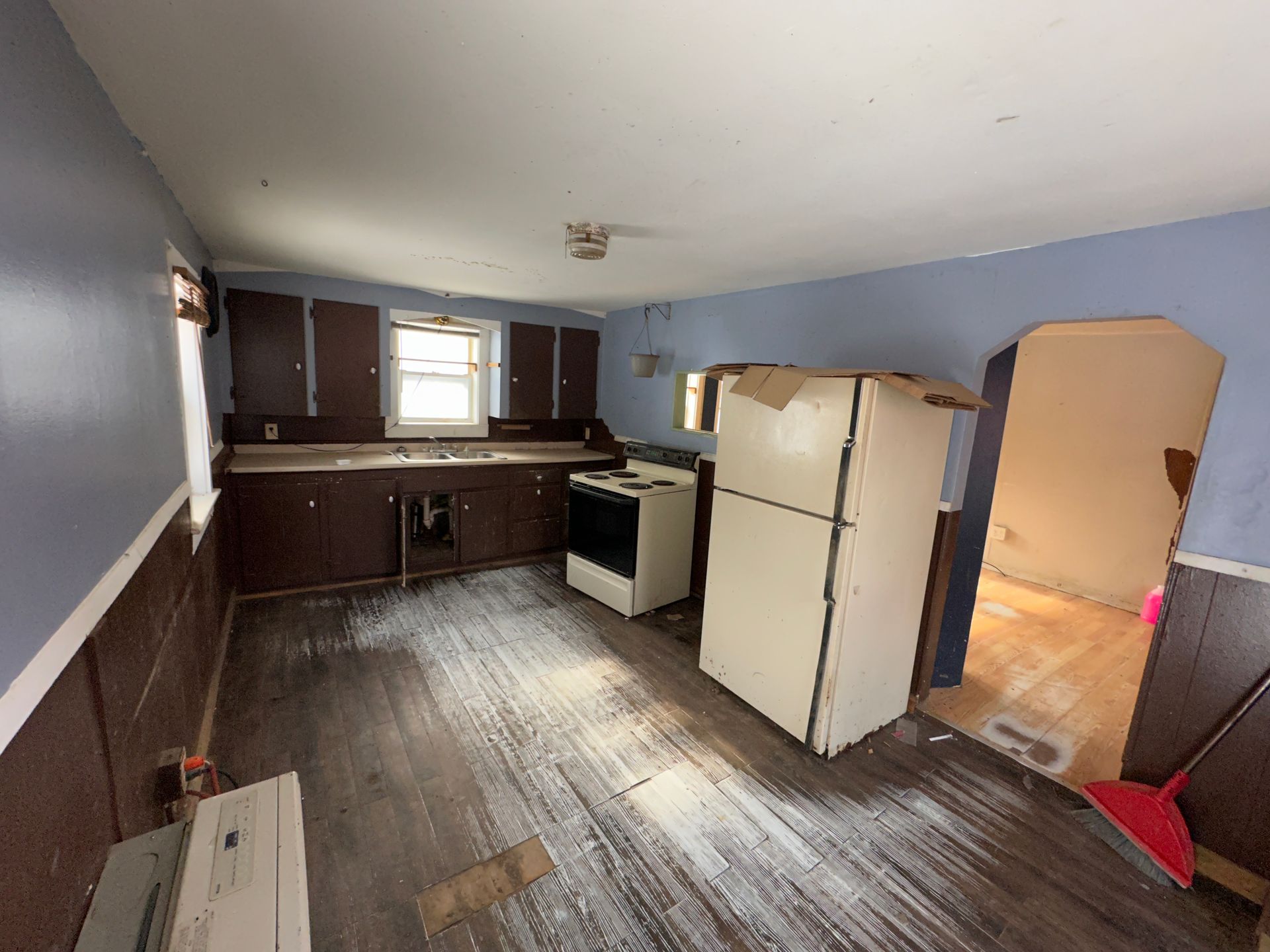 Kitchen with cabinets, appliances, and wooden floor; blue walls.